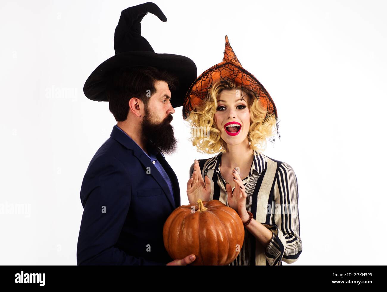 Happy couple in witches hats with pumpkin. Young people dressed at Halloween. Celebration and party. 31 october. Stock Photo