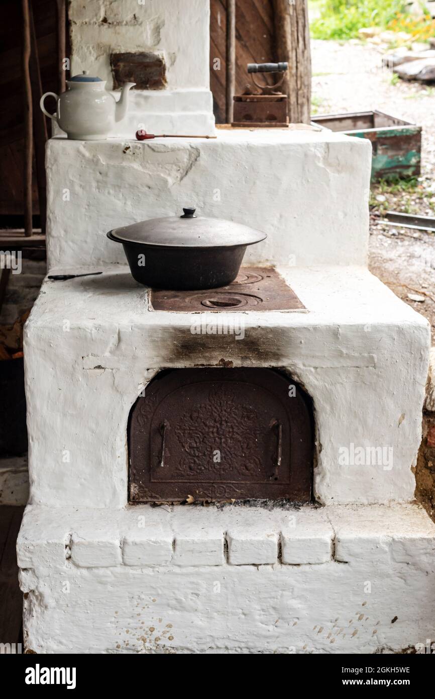 Ancient bleached stove with utensils in country house yard Stock Photo