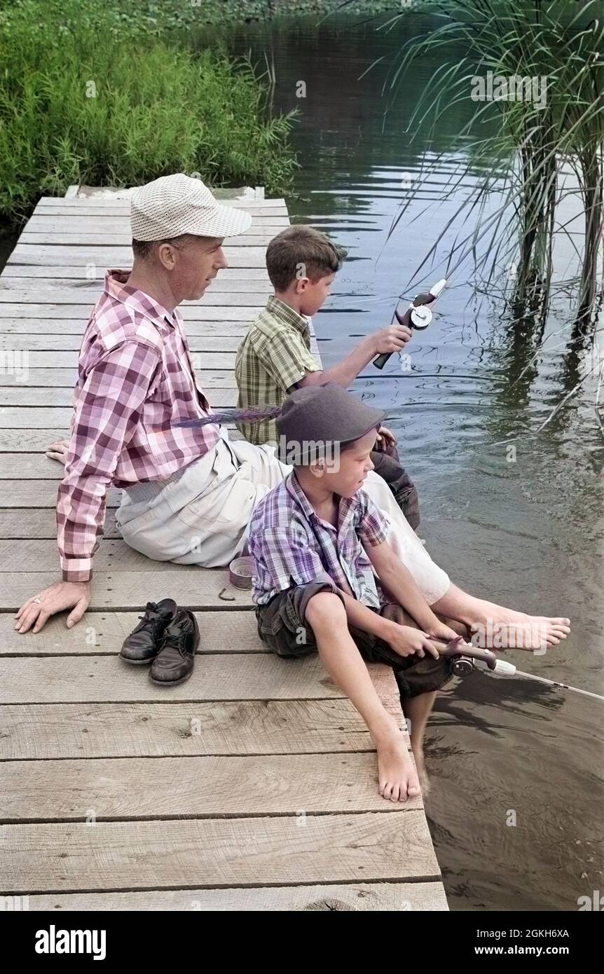 1950s 1960s FATHER WITH TWO SONS SITTING ON DOCK FISHING TOGETHER OUTDOOR  BY POND - a1979c LAN001 HARS TEACHING NOSTALGIA BROTHER OLD FASHION 1  JUVENILE POLE POND VACATION SONS FAMILIES LIFESTYLE PARENTING