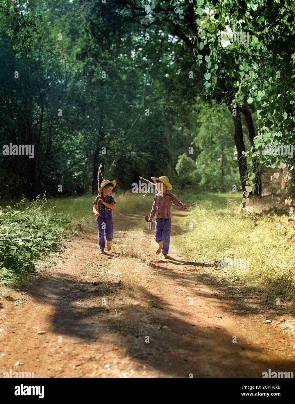 1940s 1950s TWO BOYS IN DUNGAREES PLAID SHIRTS STRAW HATS WALKING DOWN DIRT  ROAD CARRYING FISHING POLES AND CAN OF BAIT - a2326c PUN001 HARS ACTION  JEANS HIKING OLD TIME NOSTALGIA BROTHER