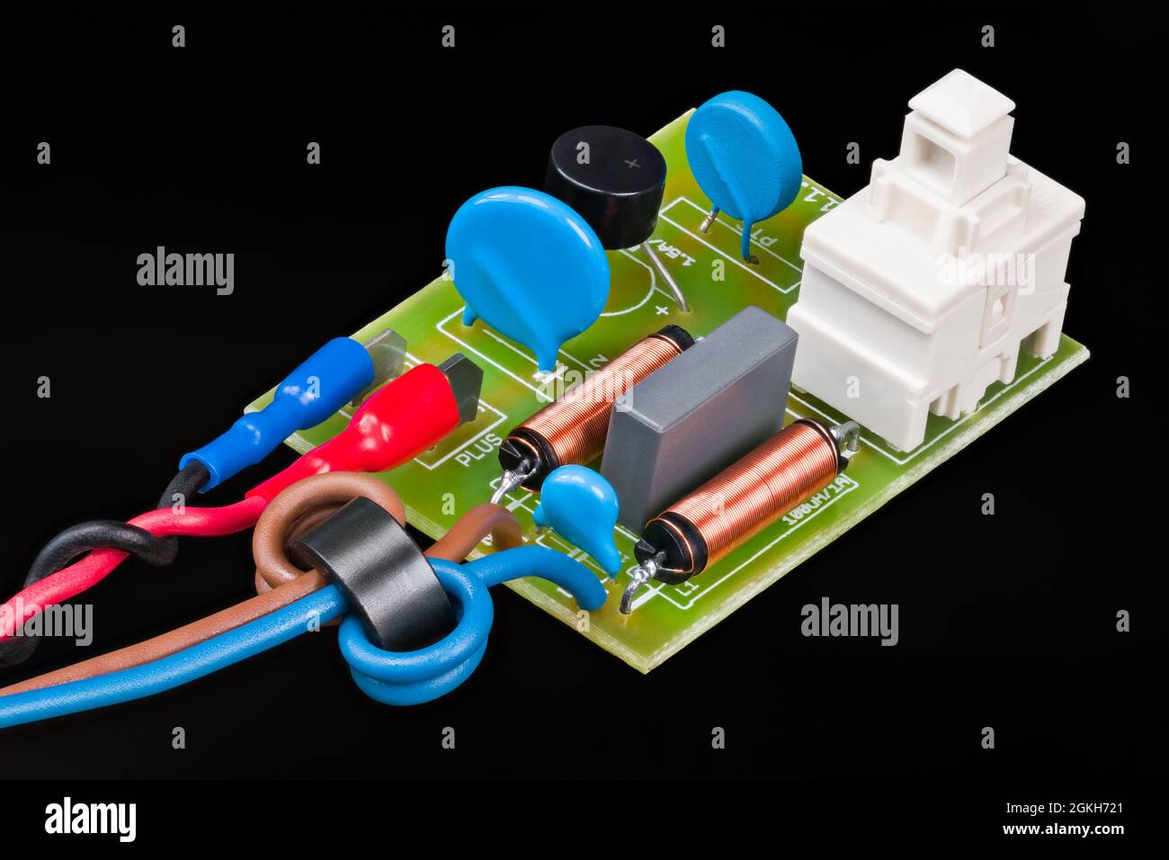 Electronic components of electric motor supply module on black background. Ferrite beads, inductors, ceramic filter capacitors or on-off switch on PCB. Stock Photo
