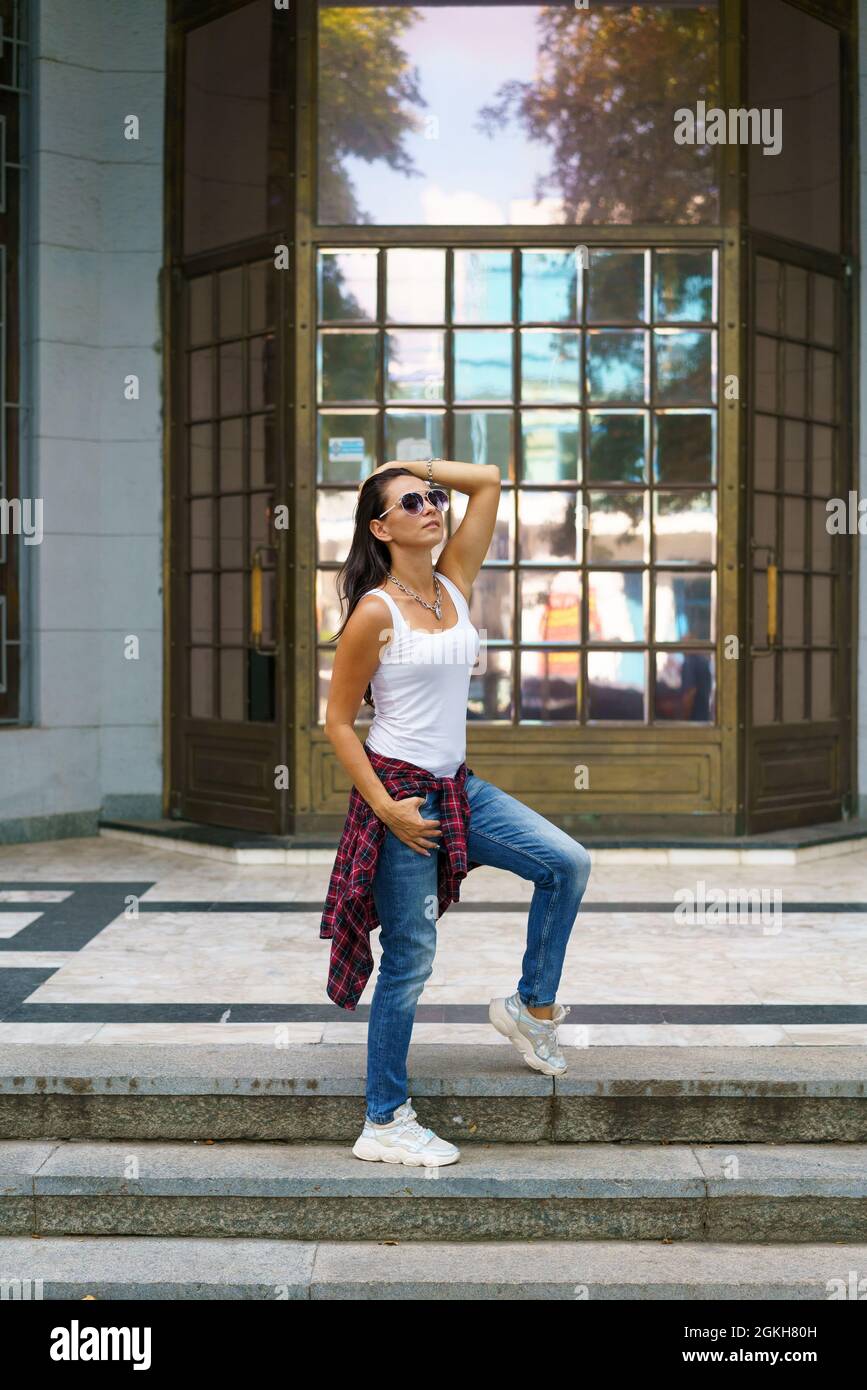 Hipster girl wearing blank white shirt and jeans posing against street  wall. Minimalist urban clothing style, street fashion. Stock Photo | Adobe  Stock