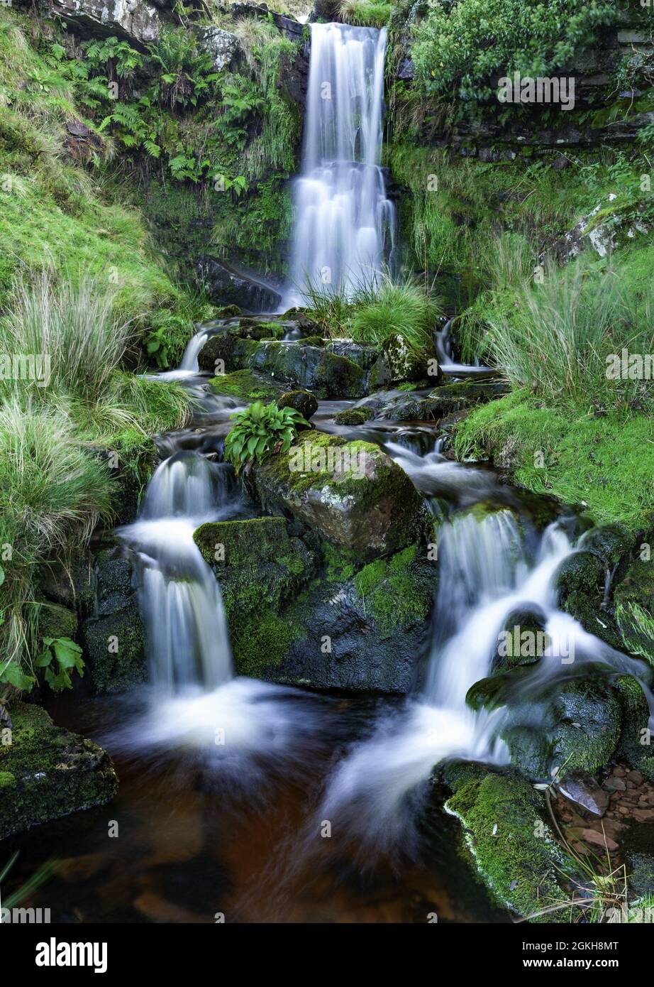 Vertical shot of a waterfall with long exposure surrounded by rocks and ...
