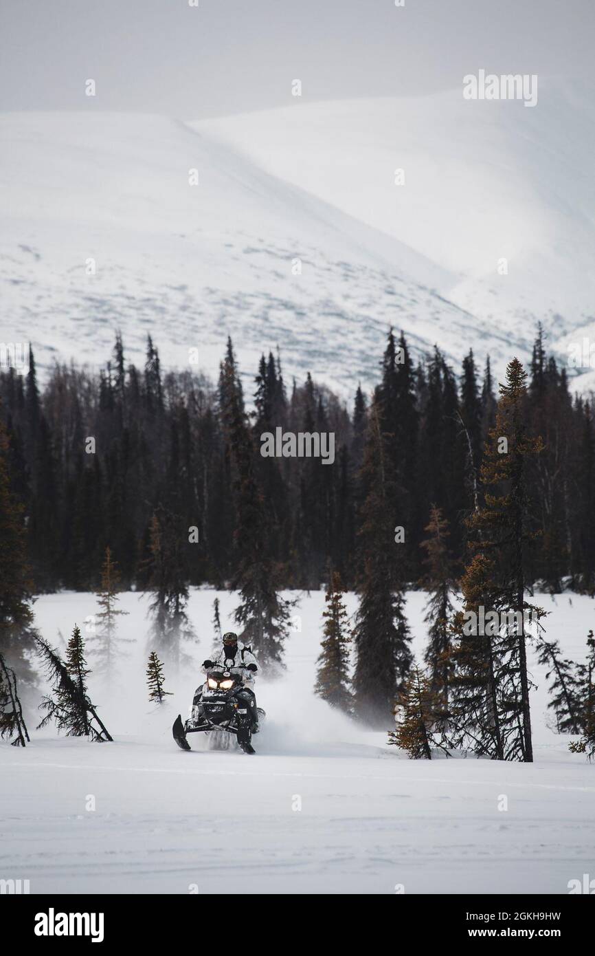 TALKEETNA, Alaska- A Green Beret with 1st Battalion, 1st Special Forces Group (Airborne), maneuvers through the Arctic tundra on a snowmobile April 2021, during an Arctic Mobility Training. The Arctic has recently developed into an international competition space and potential future battlefield that 1st SFG (A) Soldiers will have to continue to familiarize themselves with. Stock Photo