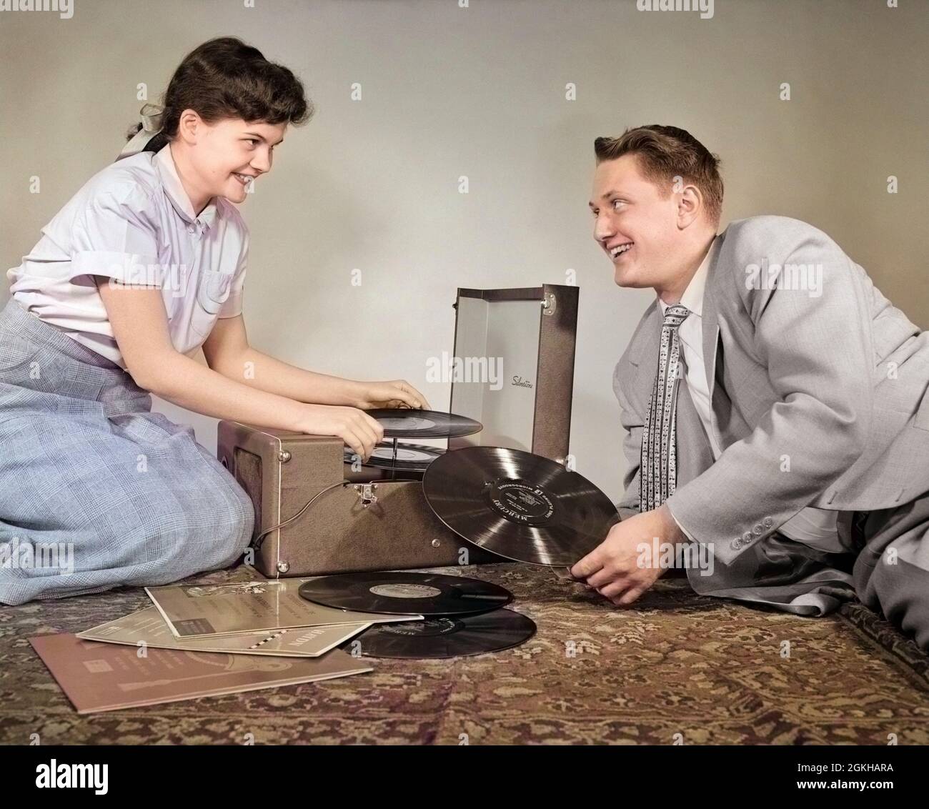 1950s TEENAGE SMILING COUPLE BOY AND GIRL SITTING ON FLOOR PLAYING VINYL MUSIC RECORDS ON PORTABLE PHONOGRAPH - j2427c LAN001 HARS OLD FASHION 1 JUVENILE STYLE COMMUNICATION YOUNG ADULT RECORDS VINYL PLEASED JOY LIFESTYLE FEMALES STUDIO SHOT HEALTHINESS HOME LIFE COPY SPACE PEOPLE CHILDREN FRIENDSHIP HALF-LENGTH PERSONS MALES TEENAGE GIRL TEENAGE BOY ENTERTAINMENT PORTABLE B&W PHONOGRAPH DATING HAPPINESS CHOICE RECORD PLAYER ATTRACTION SMILES 33 RPM COURTSHIP JOYFUL STYLISH TEENAGED YOUNG LOVE LP POSSIBILITY JUVENILES LONG-PLAYING SOCIAL ACTIVITY TOGETHERNESS YOUNG ADULT MAN YOUNG ADULT WOMAN Stock Photo