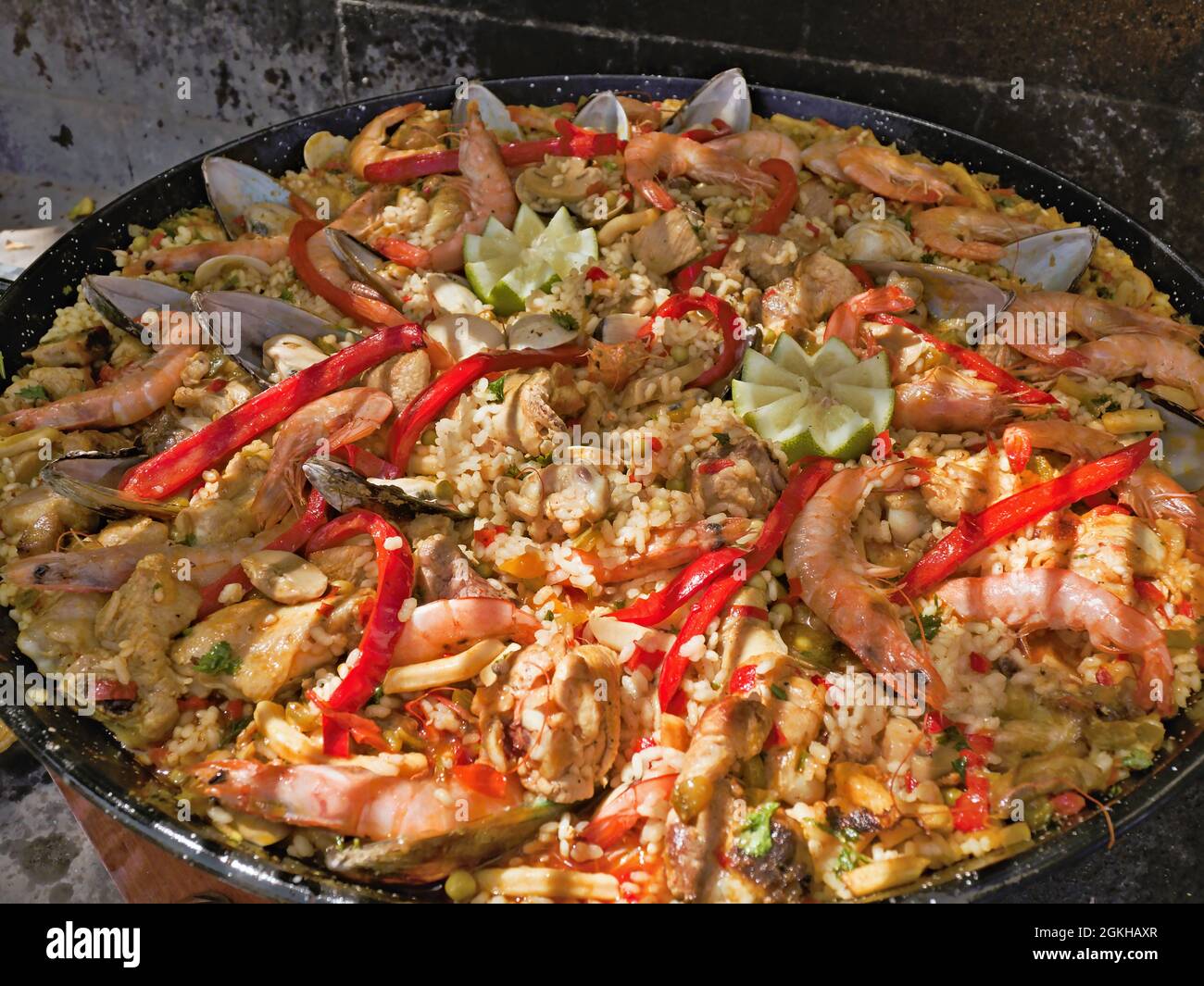 A fresh, large traditional paella with meat and seafood, garnished with lemon, in a large cast iron traditional paela pan, here on the island of Tener Stock Photo