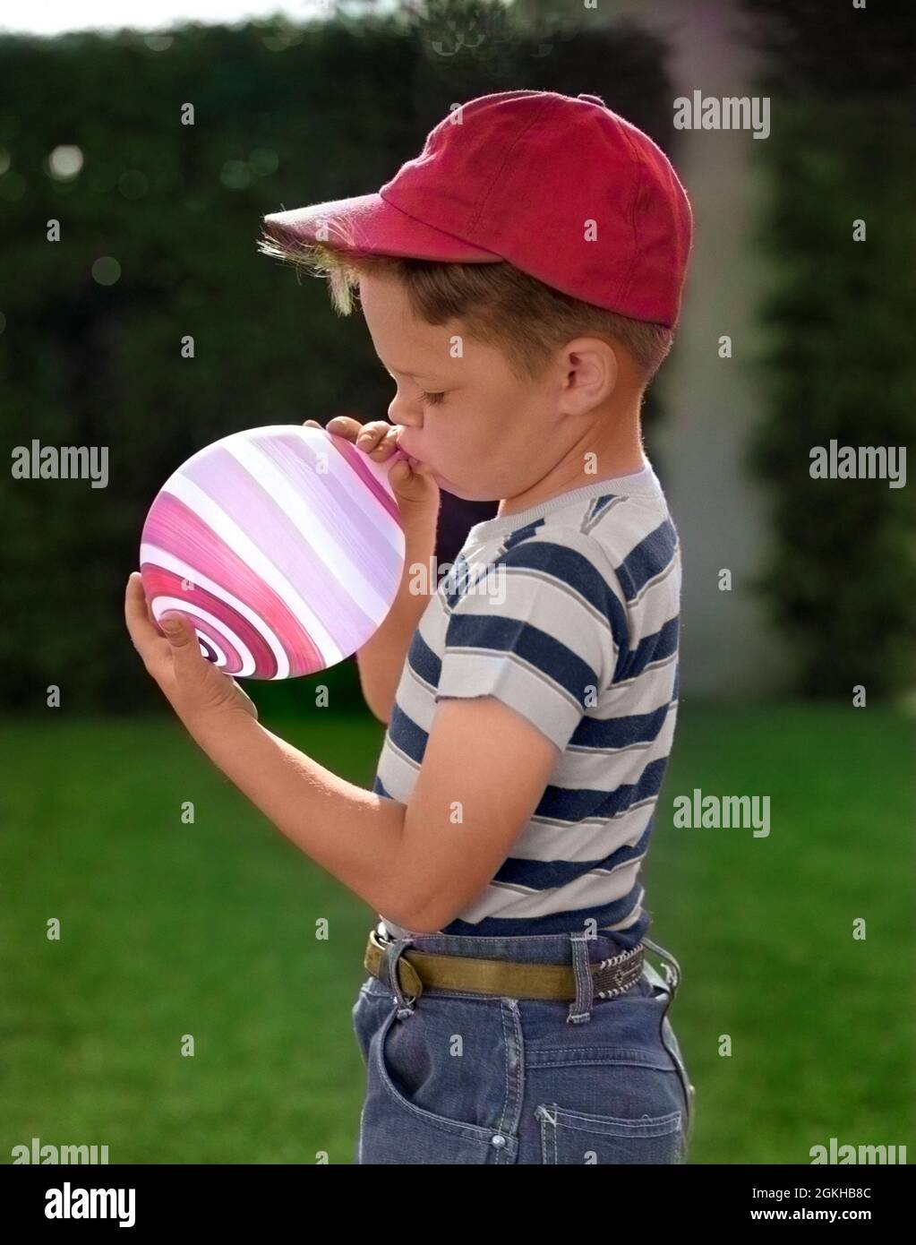 1950s PROFILE OF BOY IN BASEBALL CAP & STRIPED T-SHIRT BLOWING UP STRIPED BALLOON - j630c PUN001 HARS BLOW-UP INFLATING T-SHIRT BLOWING UP BLOWUP CHILDHOOD JUVENILES SWIRLED TASK BALL CAP BLACK AND WHITE CAUCASIAN ETHNICITY CONCENTRATION OLD FASHIONED Stock Photo