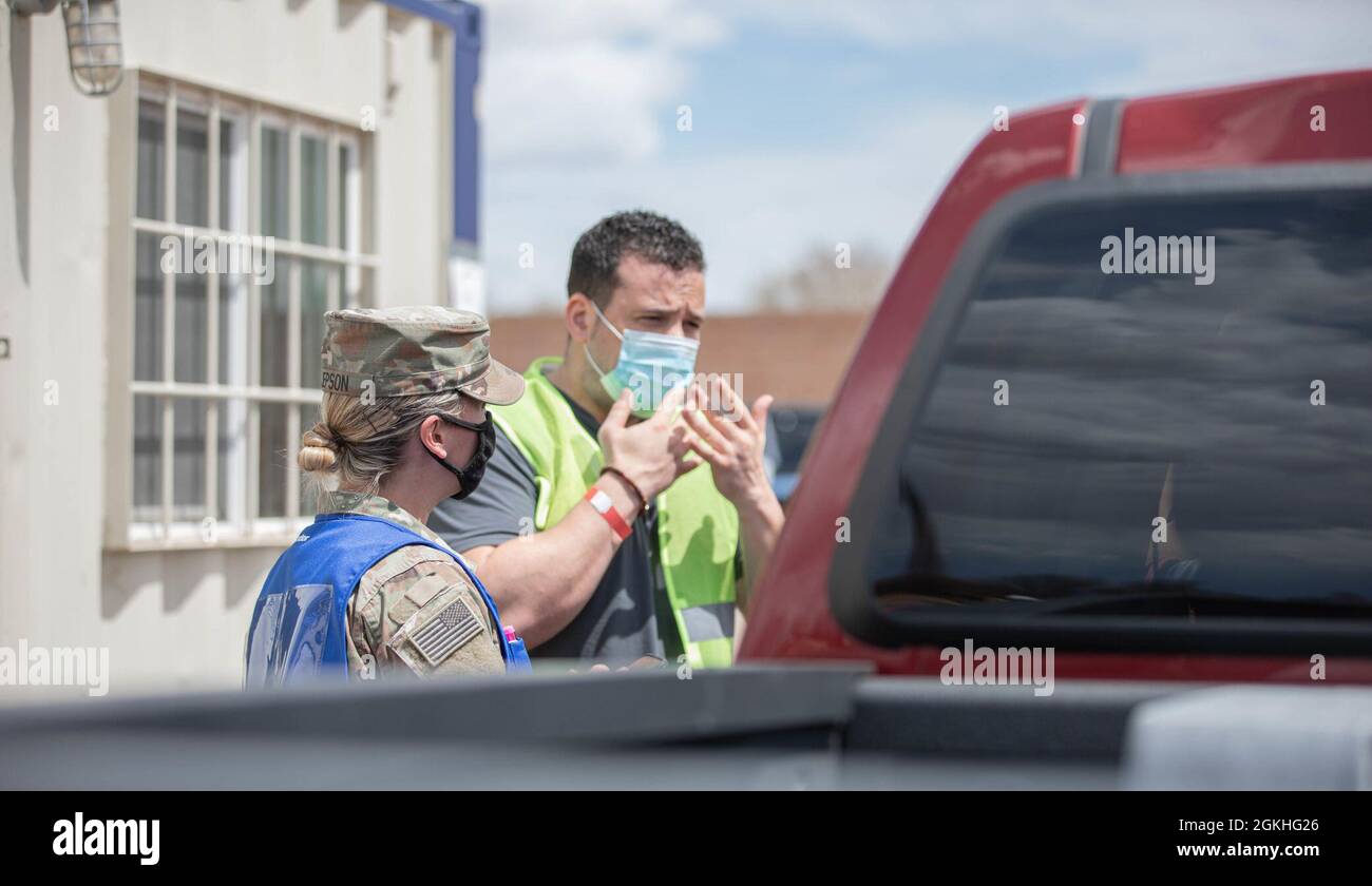 U.S. Army Soldier Spc. Kerri Jepson (left), a combat medic assigned to 2nd Stryker Brigade Combat Team, 4th Infantry Division, watches as James Pike (right), an American Sign Language interpreter with the Federal Emergency Management Agency (FEMA), communicates with members of the Pueblo community in Pueblo, Colorado, April 23, 2021. The Soldiers deployed from Fort Carson, Colorado, to provide support at the Pueblo Community Vaccination Center. U.S. Northern Command, through U.S. Army North, remains committed to providing continued, flexible Department of Defense support to the Federal Emergen Stock Photo
