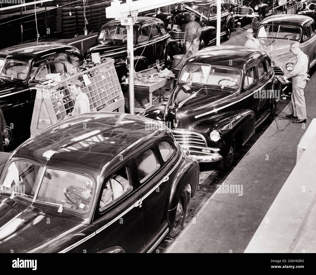 1940s SKILLED CREW OF ANONYMOUS MEN WORKING ON AUTOMOBILE ASSEMBLY LINE MANUFACTURING 1946 CHEVROLET CARS IN FLINT MICHIGAN USA - q74077 CPC001 HARS MIDDLE-AGED B&W CHEVROLET NORTH AMERICA MIDDLE-AGED MAN NORTH AMERICAN WIDE ANGLE SKILL OCCUPATION SKILLS HIGH ANGLE AUTOS CAREERS LABOR IN OF ON EMPLOYMENT MANUFACTURING OCCUPATIONS MOTION BLUR AUTOMOBILES VEHICLES 1946 FLINT SKILLED ANONYMOUS EMPLOYEE MID-ADULT MID-ADULT MAN BLACK AND WHITE CAUCASIAN ETHNICITY LABORING MI OLD FASHIONED Stock Photo