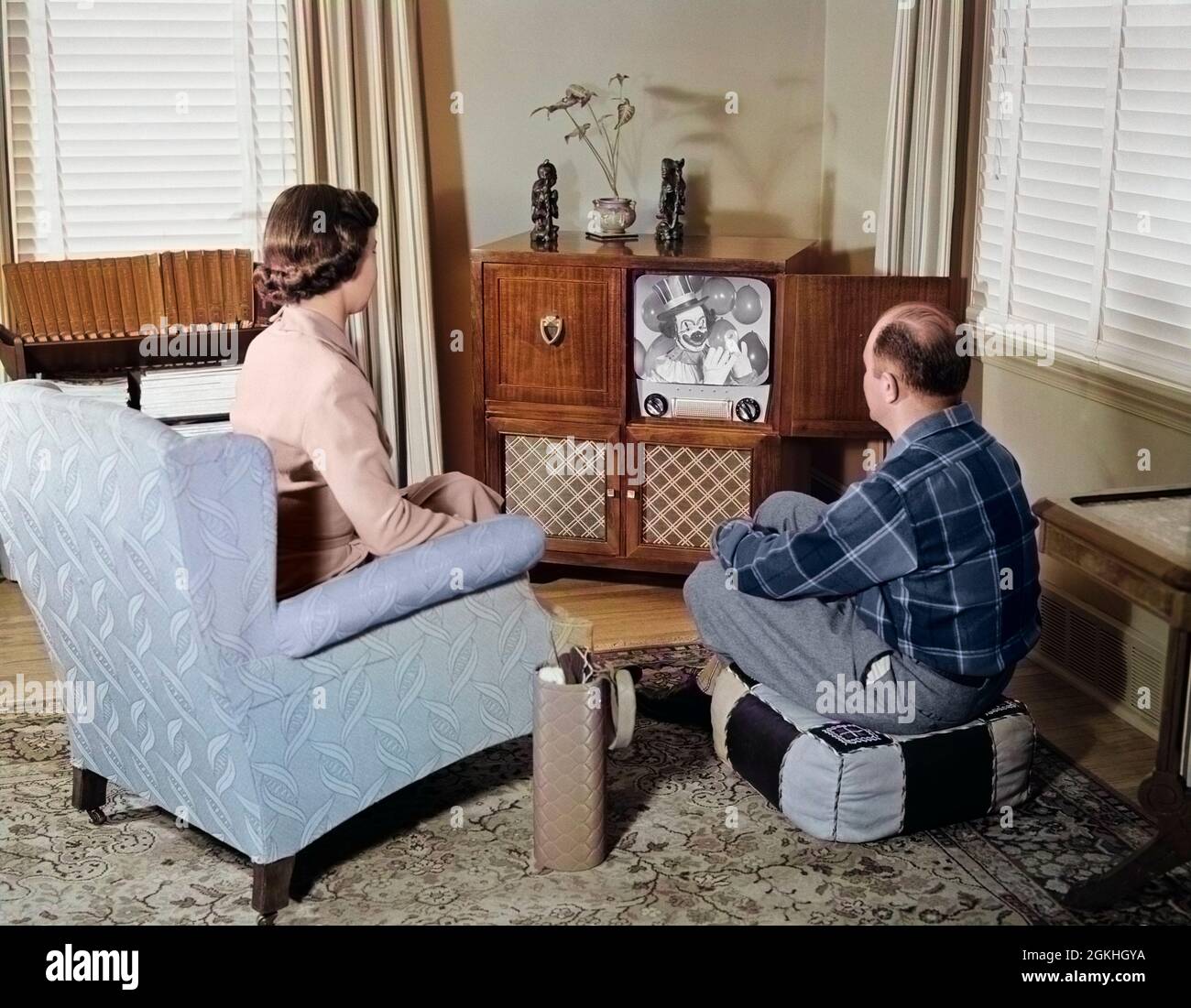 1950s MIDDLE AGE COUPLE HUSBAND AND WIFE SITTING WATCHING BLACK AND WHITE CONSOLE TELEVISION IN LIVING ROOM - r10114c HAR001 HARS GROWN-UP MALES ENTERTAINMENT TELEVISIONS CONSOLE DREAMS ST LEISURE LIVING ROOM EXCITEMENT ESCAPE OTTOMAN BACK VIEW COMMUNICATE COMMUNICATIONS MID-ADULT MID-ADULT MAN MID-ADULT WOMAN TOGETHERNESS WIVES CAUCASIAN ETHNICITY HAR001 OLD FASHIONED Stock Photo