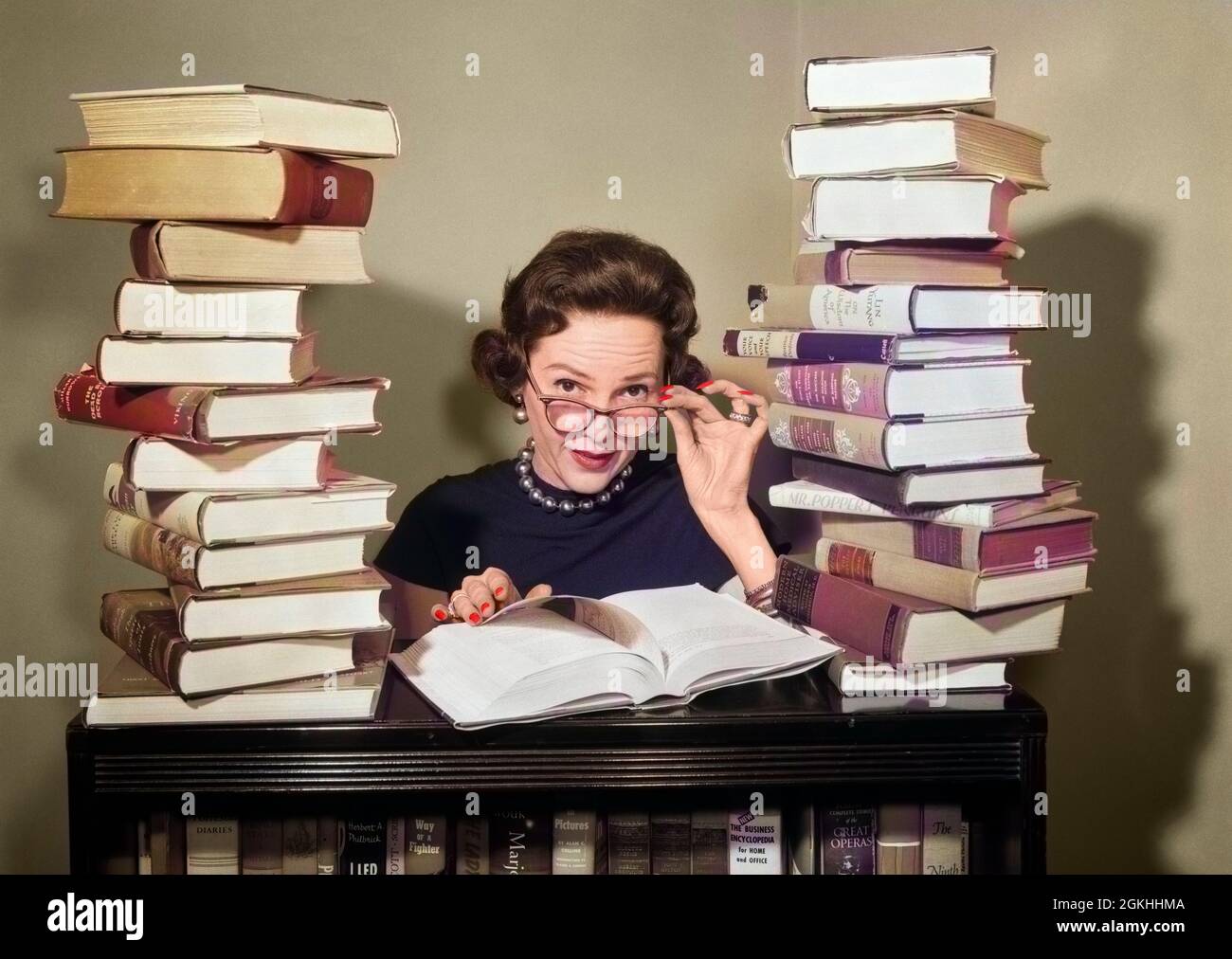 1950s WOMAN LIBRARIAN SITTING BETWEEN STACKS OF BOOKS PULLING DOWN GLASSES TO LOOK OVER RIMS LOOKING AT CAMERA - r843c DEB001 HARS READ OLD FASHION 1 FACIAL COMMUNICATION CAREER YOUNG ADULT INFORMATION WEAR LIFESTYLE FEMALES JOBS GROWNUP COMMUNICATING HORIZONTAL COPY SPACE LADIES MASS PERSONS PROFESSION EYEGLASSES B&W MASS MEDIA EYE CONTACT RELEASES PROFESSOR SKILL OCCUPATION OPTICAL SKILLS HEAD AND SHOULDERS LITERATE EYE WEAR CAREERS KNOWLEDGE RESEARCHER BETWEEN EMPLOYMENT OCCUPATIONS READER STACKS DEB001 EMPLOYEE RIMS COMMUNICATE COMMUNICATIONS MID-ADULT MID-ADULT WOMAN QUESTIONING STUDIOUS Stock Photo