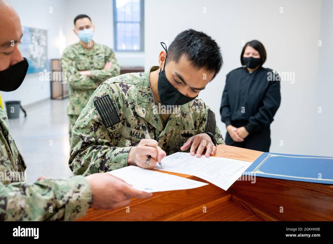 WASHINGTON, DC (April 23, 2021) – Religious Program Specialist 2nd Class Arvin Malin signs reenlistment paperwork following a ceremony held onboard Washington Navy Yard. Stock Photo