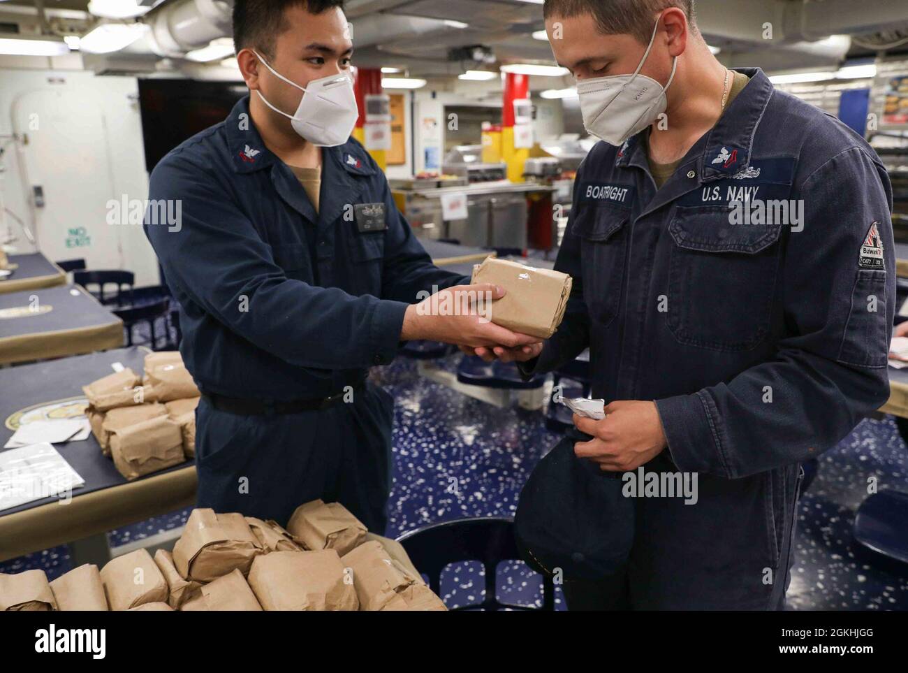 IRISH SEA (April 24, 2021) Culinary Specialist 2nd Class Jose Ramos, president of the junior enlisted association (JEA) aboard the Arleigh Burke-class guided-missile destroyer USS Ross (DDG 71), left, hands a care package to Boatswain’s Mate 2nd Class David Boatright as JEA assists the ship’s chapel in handing out cards and care packages sent by East Side Lutheran Church in Sioux Falls, South Dakota to the crew while underway in the Irish Sea, April 24, 2021. Ross, forward-deployed to Rota, Spain, is on patrol in the U.S. Sixth Fleet area of operations in support of regional allies and partner Stock Photo