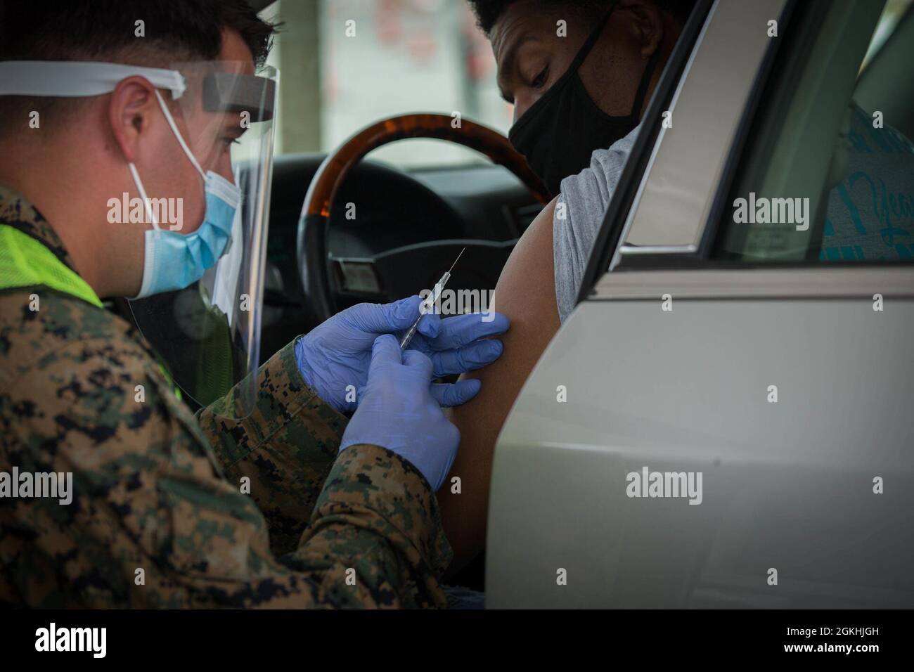 U.S. Sailor Petty Officer 1st Class Thomas Arnold, 1st Medical Battalion,  Charlie Company, Camp Pendleton California, administers the COVID-19  vaccine to a community member at the Community Vaccination Center at the Bon