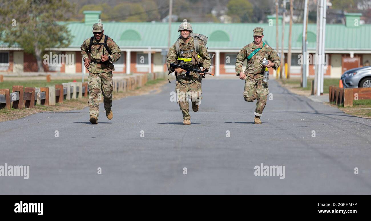 U.S. Army Spc. Noah Mayes, center, a military police officer assigned to the 143rd Military Police Company, 192nd Military Police Battalion, Connecticut Army National Guard, runs down 1st Street alongside U.S. Army 1st Sergeant Jose Rodriguez, left, assigned to the 1048th Medium Truck Company, 143rd Combat Sustainment Support Battalion, Connecticut Army National Guard, and U.S. Army Sgt. Michael Gosslin, right, assigned to the 143rd Military Police Company, 192nd Military Police Battalion, Connecticut Army National Guard, during a ruck march at Camp Nett, Niantic, Connecticut, April 24, 2021. Stock Photo