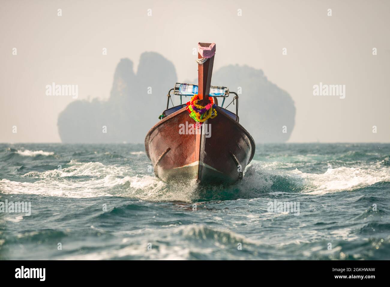 Longtail boat sailing at full throttle across the Andaman Sea leaving Phi Phi island in the background. Stock Photo
