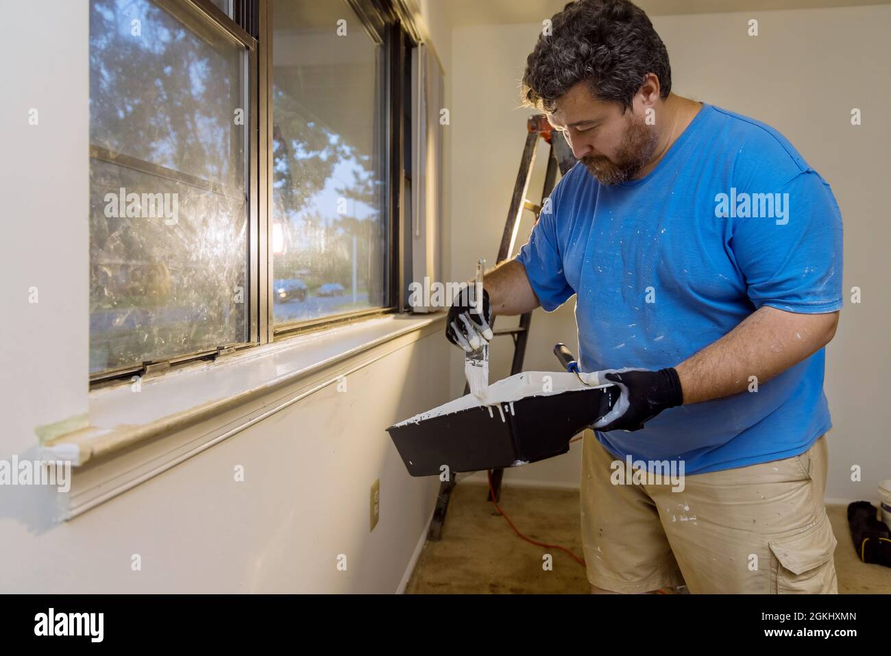 Home renovation in the handyman paints with a paint brush a window