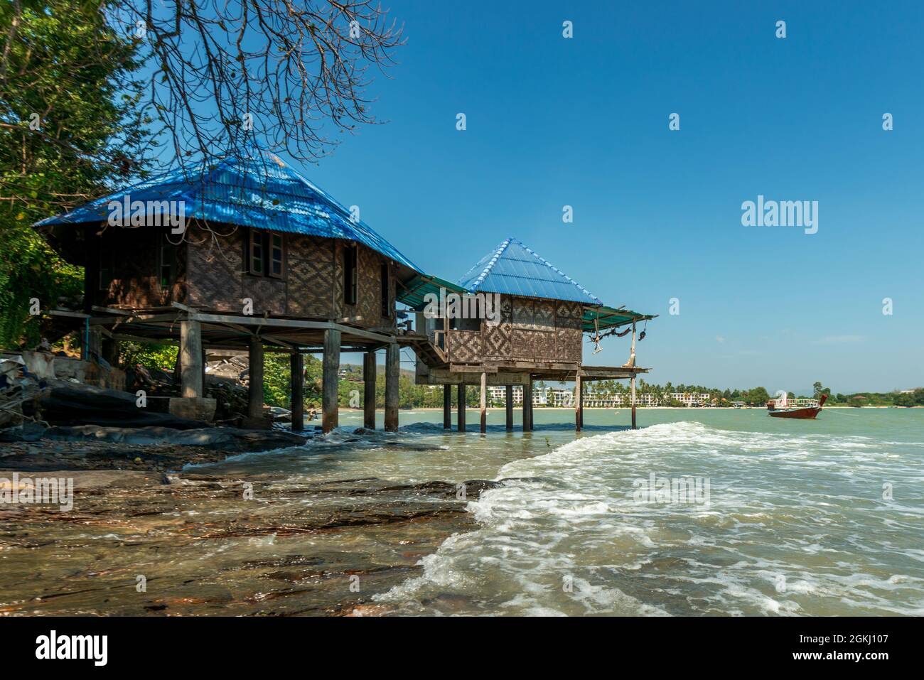 blue roofed bungalows suspended on stilts over the water near a Phuket
