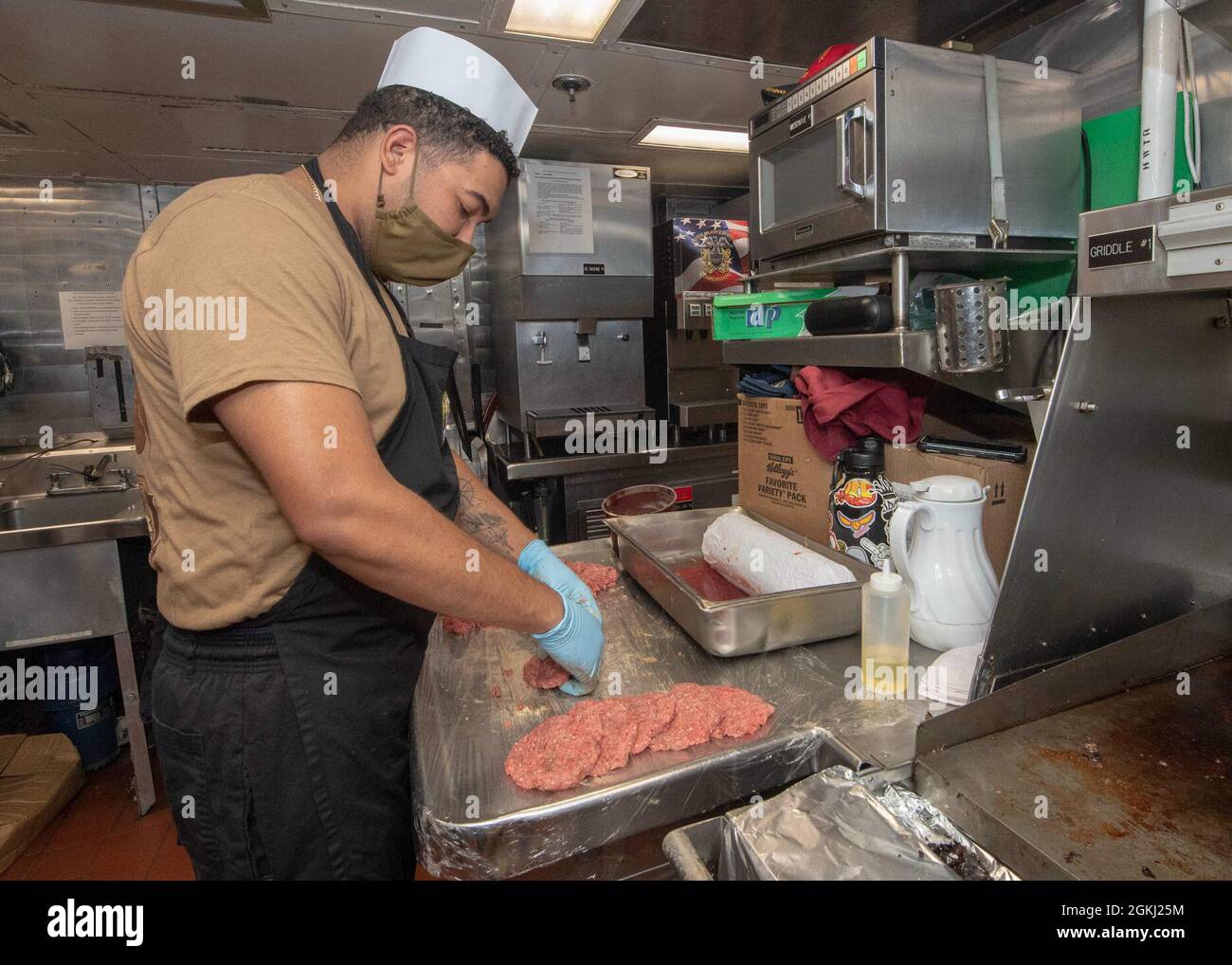 PACIFIC OCEAN (April 28, 2021) U.S. Navy Culinary Specialist Seaman Steven Rodriguez, from Bronx, N.Y., shapes hamburger patties in the galley of the Ticonderoga-class guided-missile cruiser USS Bunker Hill (CG 52) April 28, 2021. Bunker Hill, part of the Theodore Roosevelt Carrier Strike Group, is on a scheduled deployment conducting routine operations in U.S. 3rd Fleet. Stock Photo