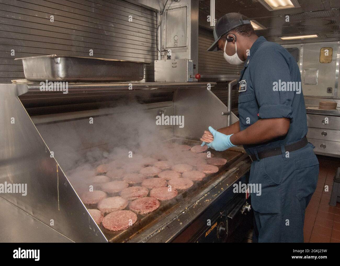 PACIFIC OCEAN (April 28, 2021) U.S. Navy Culinary Specialist 3rd Class Tilman Ware, from Abilene, Texas, cooks hamburgers in the galley of the Ticonderoga-class guided-missile cruiser USS Bunker Hill (CG 52) April 28, 2021. Bunker Hill, part of the Theodore Roosevelt Carrier Strike Group, is on a scheduled deployment conducting routine operations in U.S. 3rd Fleet. Stock Photo
