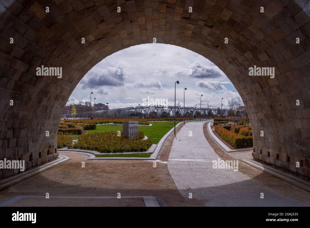 View of the Madrid river park with a metal walkway in the background from under an arch of the Toledo bridge Stock Photo