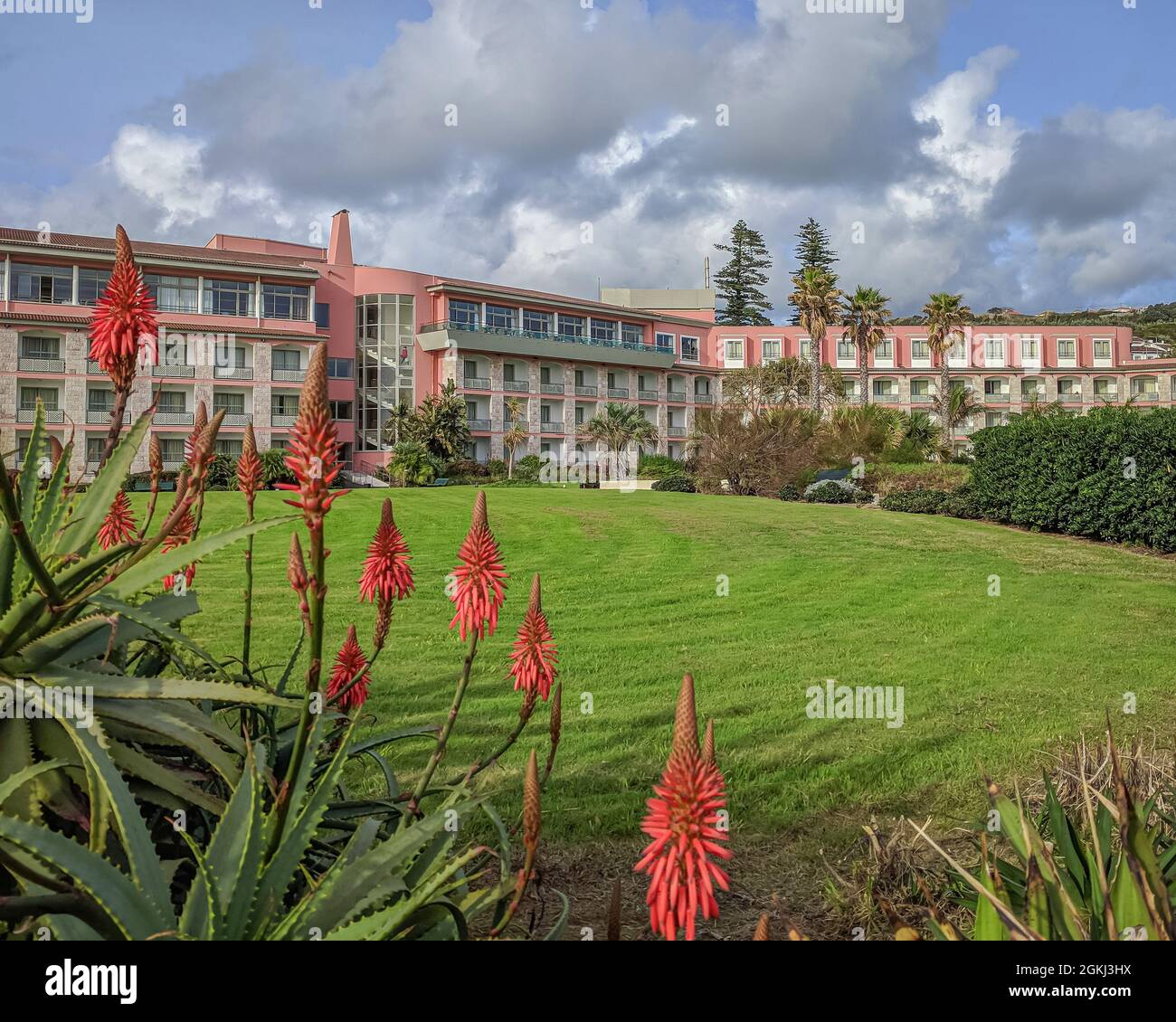 A landscaped lawn with orange aloe flowers below the back of the Terceira Mar Hotel in Angra do Heroismo, Azores Stock Photo