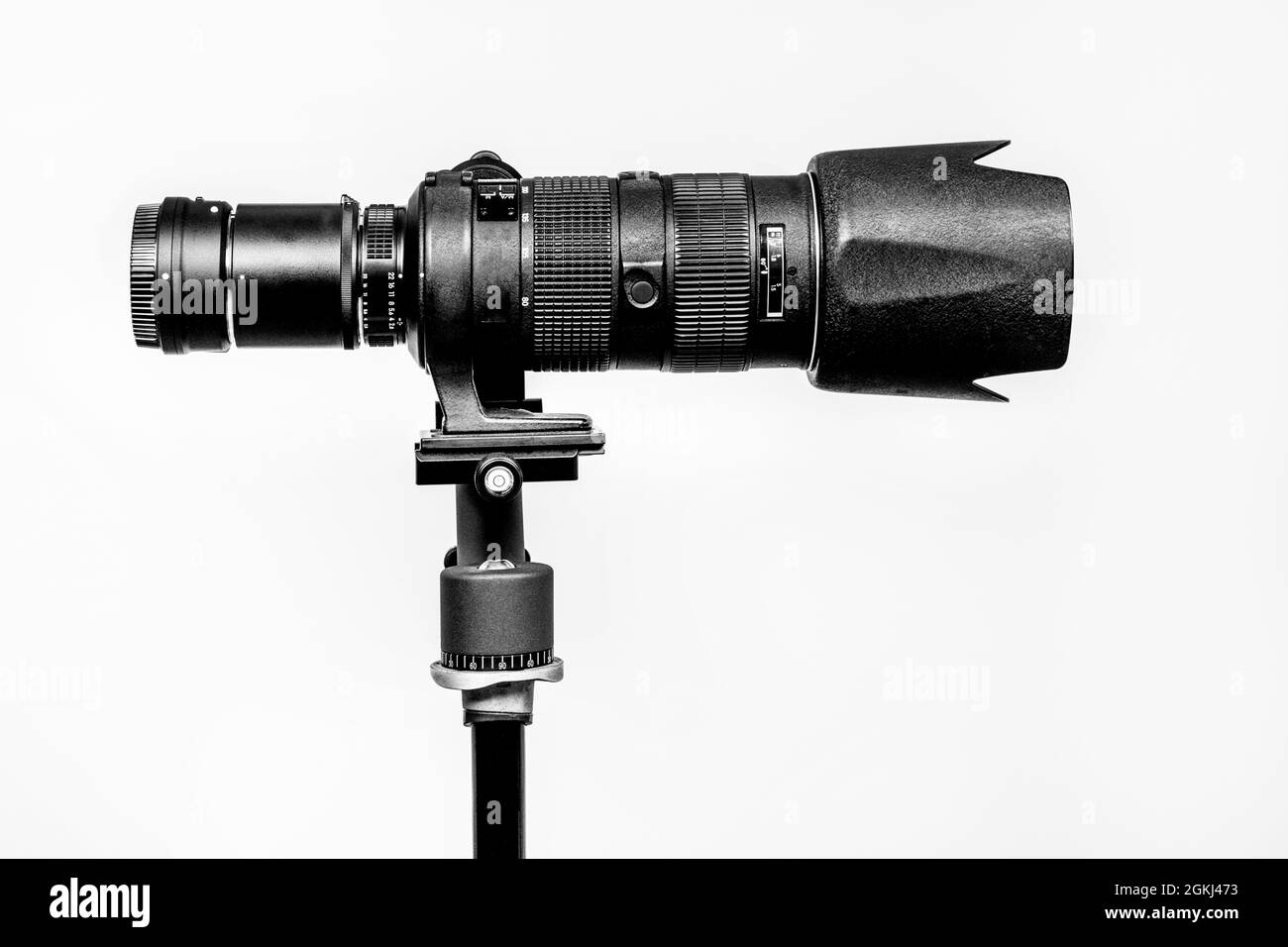 Black telephoto lens, duplicator, tripod and gimbal head on white