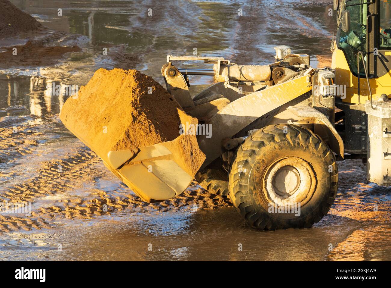 Tractor front wheel loader with sand in bucket. Earthmoving works at