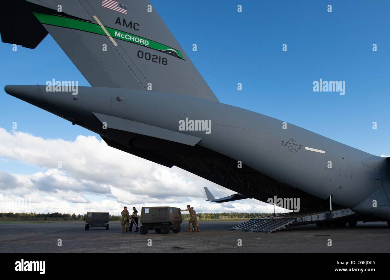 U.S. Air Force Airmen assigned to the 62nd Aerial Port Squadron push a ...