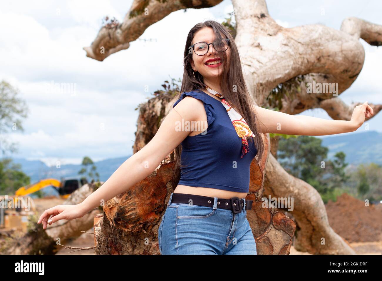 Teenager in with her arms outstretched near a lying log. Earthy, autumnal tones. Stock Photo