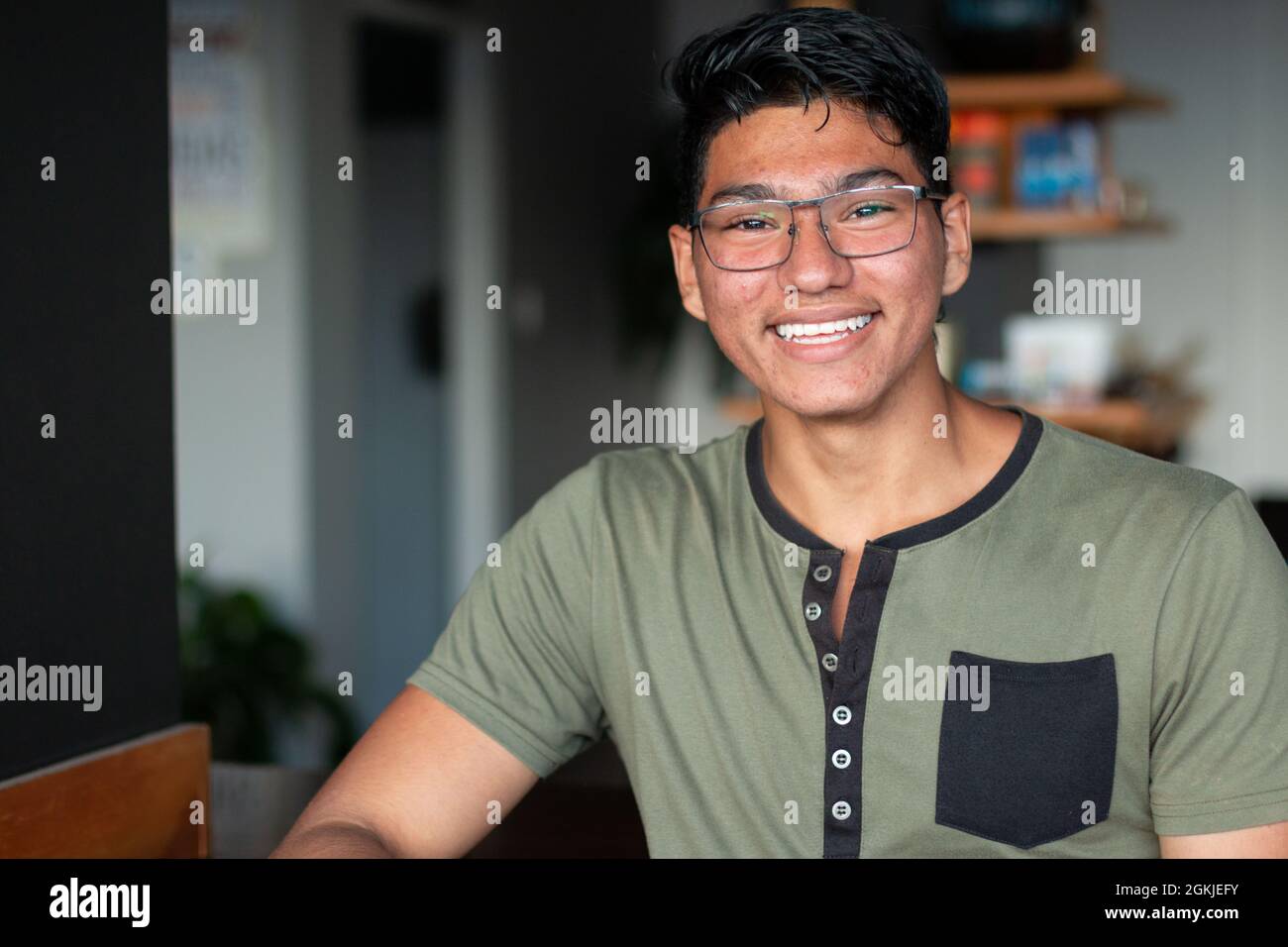 Adolescent man with glasses smiling and looking confident with acne on skin. Stock Photo