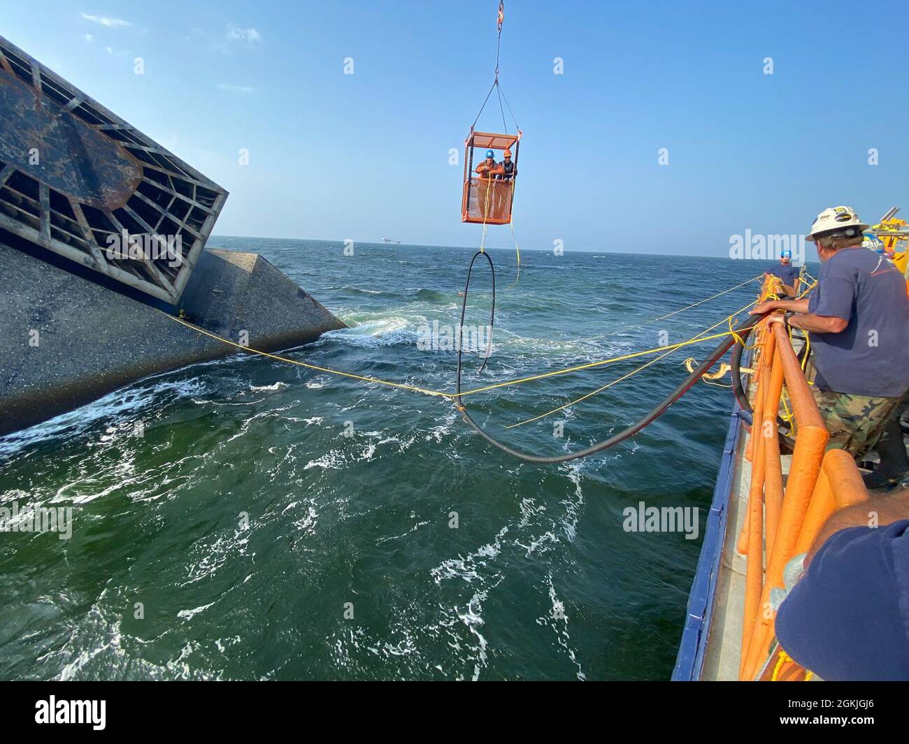 Contacted salvage divers transport a hose to the SEACOR Power fuel tank to start removing the fuel, May 3, 2021, off Port Fourchon, Louisiana. Good weather conditions are imperative for diver safety and smooth, steady operations. Stock Photo