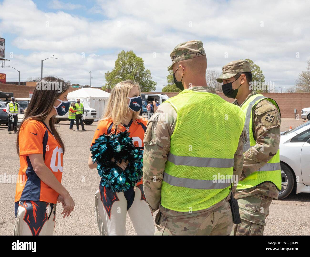 U.S. Army Sgt. James Hines, middle right, and U.S. Army Pfc. Eloy Martinez, far right, cavalry scouts assigned to 3rd Squadron, 61st Calvary Regiment, speak with cheerleaders of the Denver Broncos at the Community Vaccination Center (CVC) at the Colorado State Fairgrounds in Pueblo, Colorado, May 4, 2021. The Denver Broncos mascot and cheerleaders visited the Pueblo CVC to support Soldiers and community members. U.S. Northern Command, through U.S. Army North, remains committed to providing continued, flexible Department of Defense support to the Federal Emergency Management Agency as part of t Stock Photo