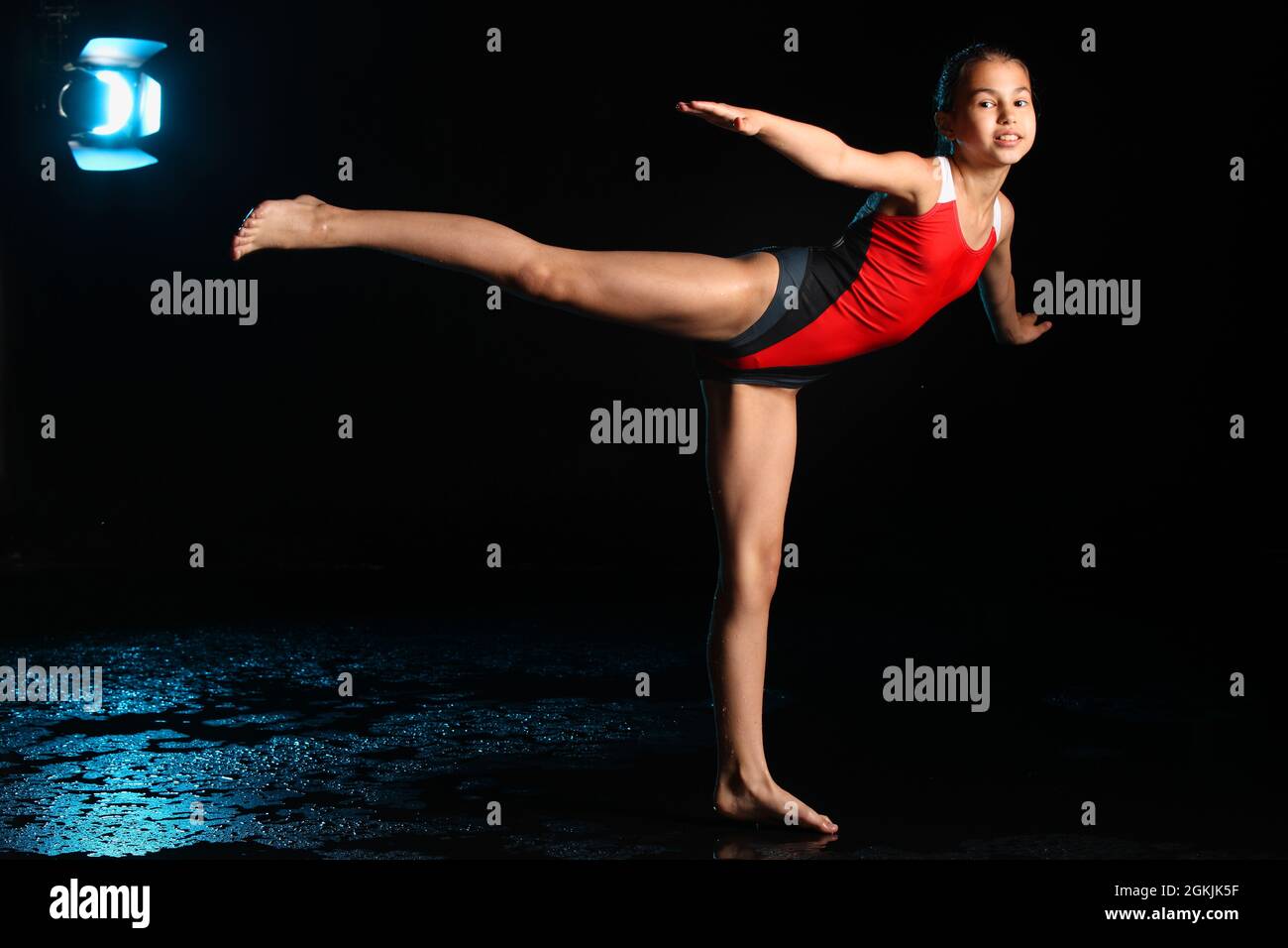 A beautiful and slender teenage girl in a red one-piece swimsuit is