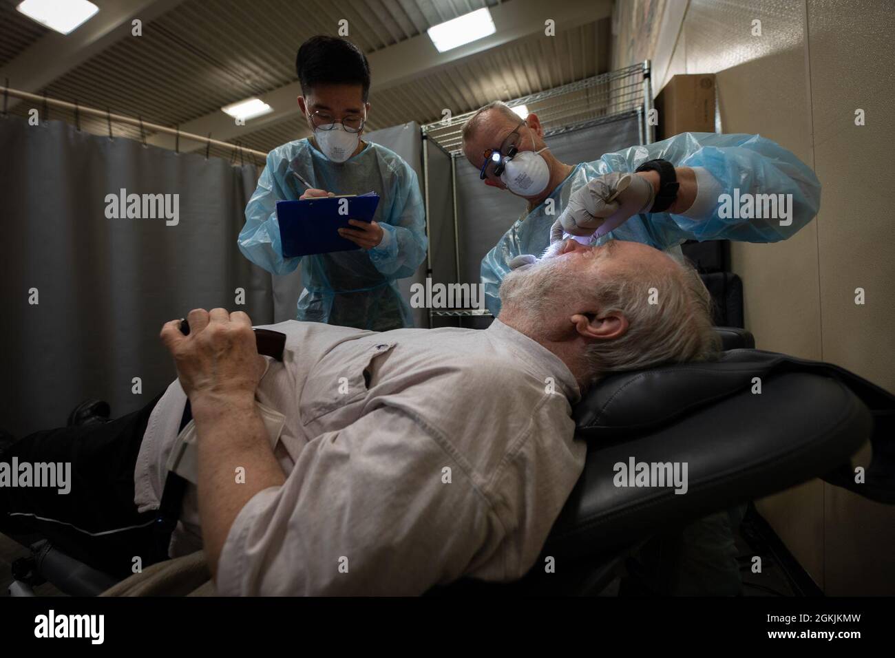 U.S. Air National Guard Major Raymond Martin, 102nd Medical Group, 102nd Intelligence Wing, along with a U.S. Army Soldier, conduct a dental exam for a Kodiak Island resident during Arctic Care 2021 in Kodiak, Alaska, on May 5, 2021. Arctic Care 2021 provides medical troops and support personnel “hands-on” readiness training while providing no-cost medical care to the people of Kodiak, Alaska. Stock Photo