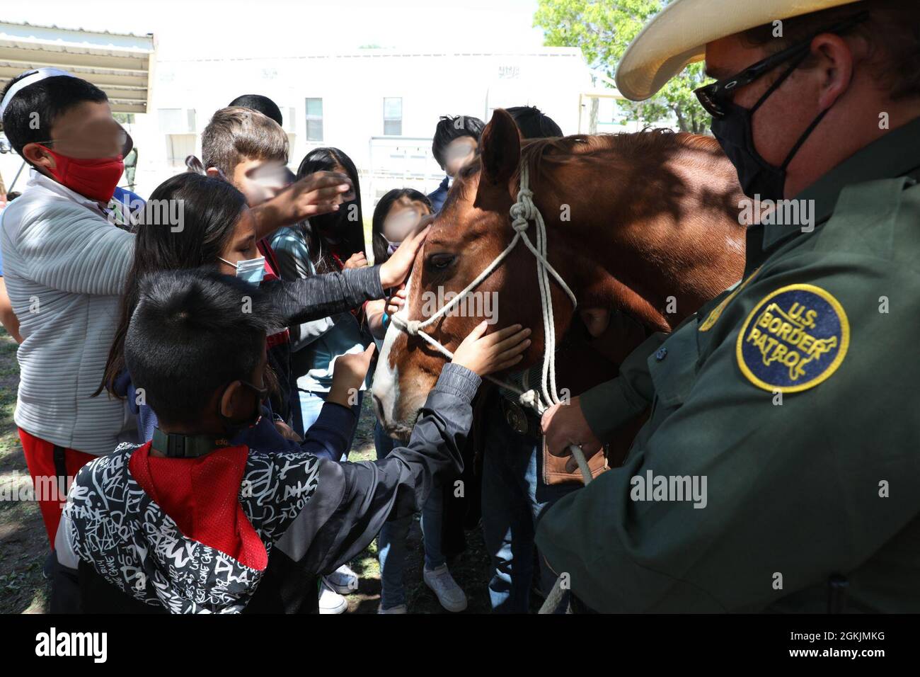 A Big Bend Sector Horse Patrol agent talks with school children from the Van Horn Independent School District as they pet 'Trigger' during an open house event May 5, 2021, Big Bend Sector Headquarters, Marfa, Texas. Many school-aged children attended the event to learn about the law-enforcement mission CBP agents perform and the tools used such as horse patrol, specialized vehicles, and helicopters. Faces have been blurred to protect the privacy of the individuals shown. Stock Photo