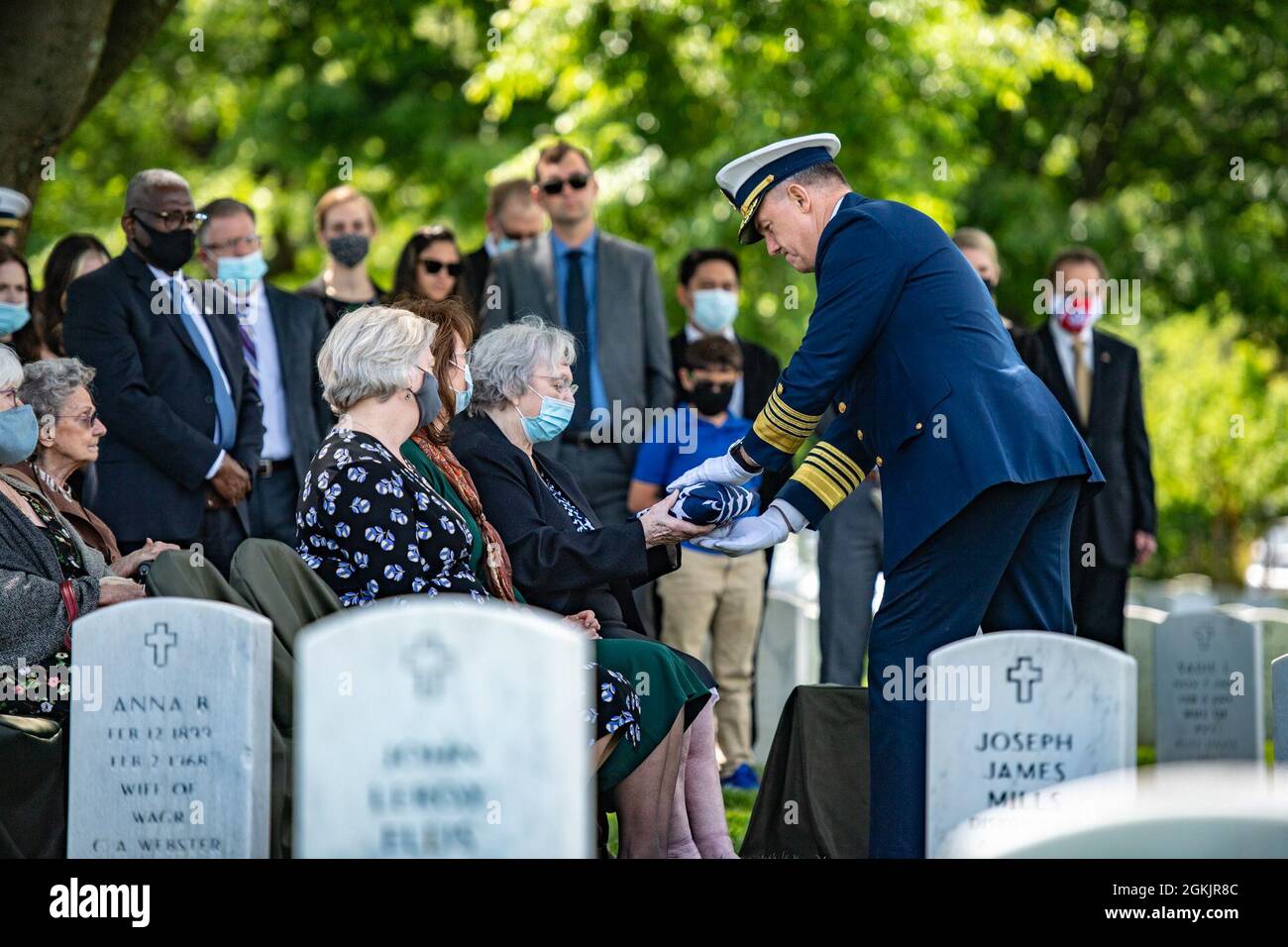The 26th Commandant of the U.S. Coast Guard Adm. Karl Schultz presents the U.S. flag to Melinda Gilbert during the funeral service of Gilbert's husband, U.S. Coast Guard Rear Adm. Marshall E. Gilbert, in Section 33 of Arlington National Cemetery, Arlington, Virginia, May 6, 2021.     Rear Adm. Gilbert was a distinguished leader in the U.S. Coast Guard and helped create the technical standards for electronic communications, navigation, and distress alerting used worldwide.     Read more about Rear Adm. Gilbert’s service here: https://www.history.uscg.mil/Browse-by-Topic/Notable-People/All/Artic Stock Photo