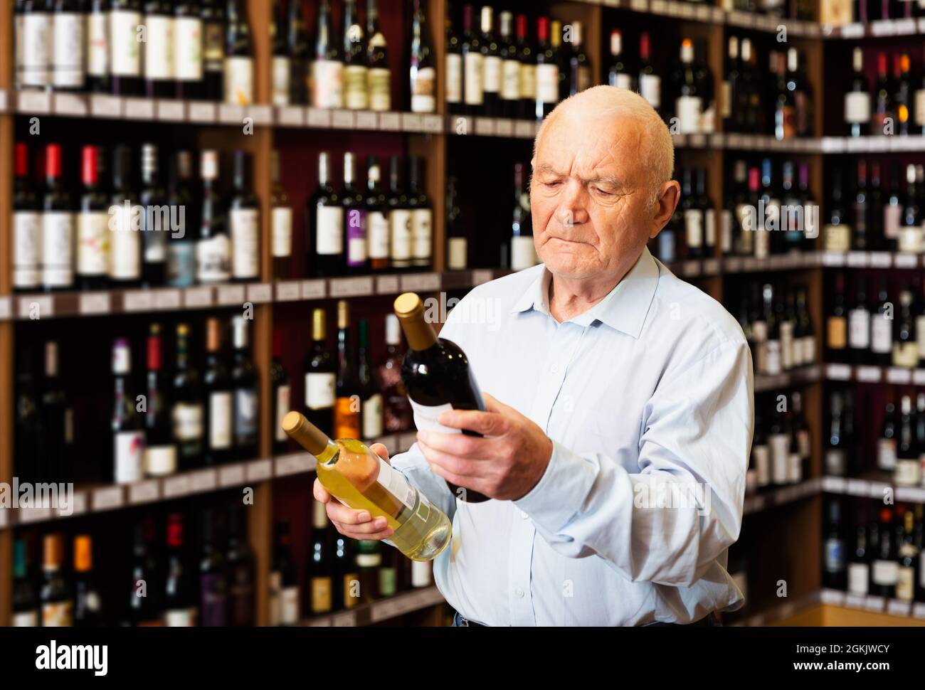 man chooses between red and white wine Stock Photo