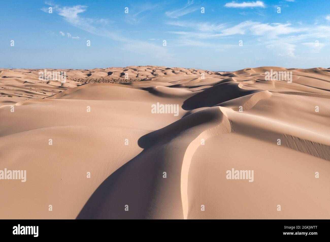 Large sand dunes with texture, patterns, light and shadow. Blue sky with white clouds Stock Photo