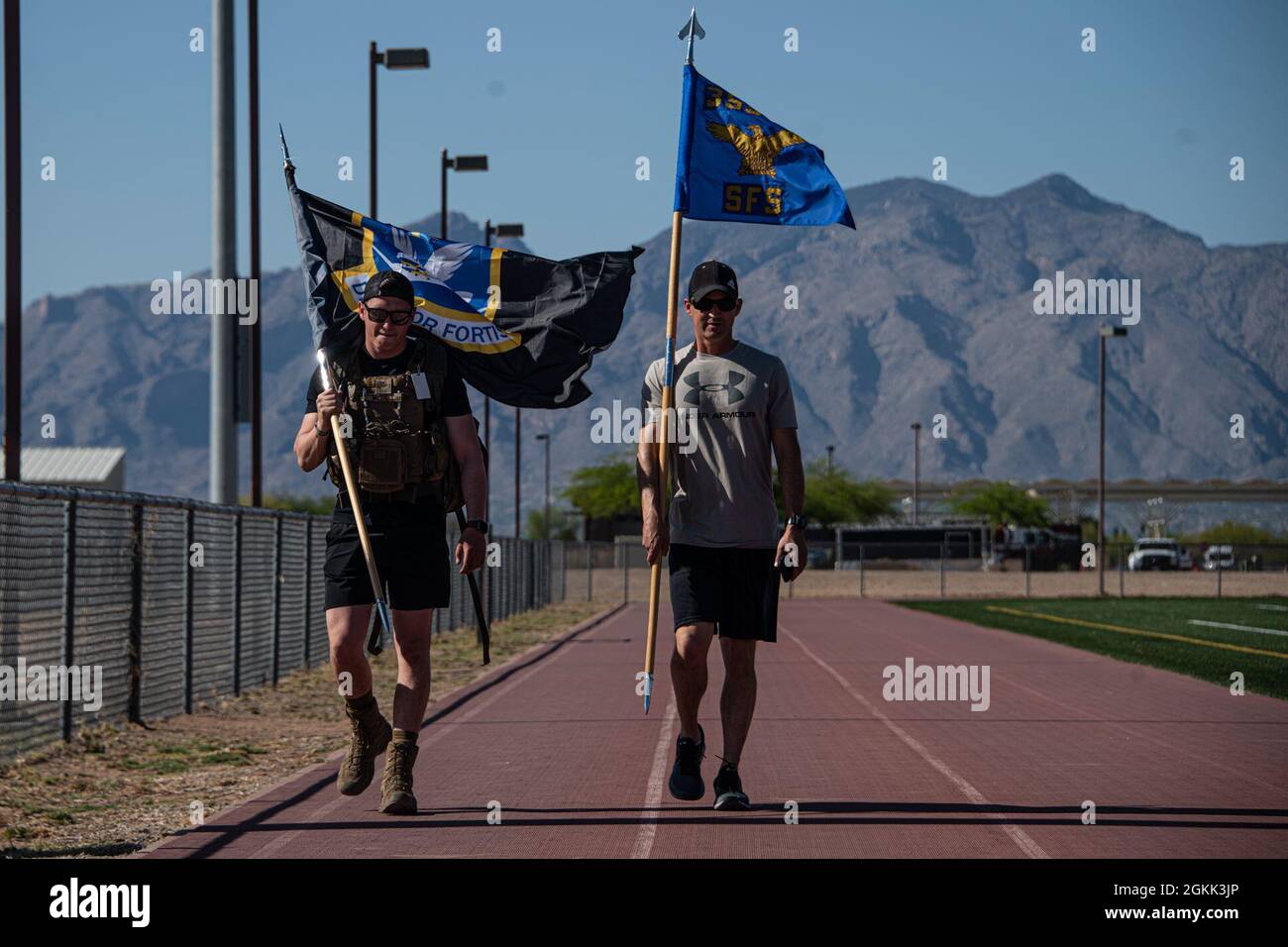 Airmen walk on the outdoor track at Davis-Monthan Air Force Base, Ariz., May 11, 2021. Airmen carried the 355th Security Forces Squadron guidon and a flag with the SFS logo during a 16-hour memorial walk as part of a series of events recognizing Police Week. Stock Photo