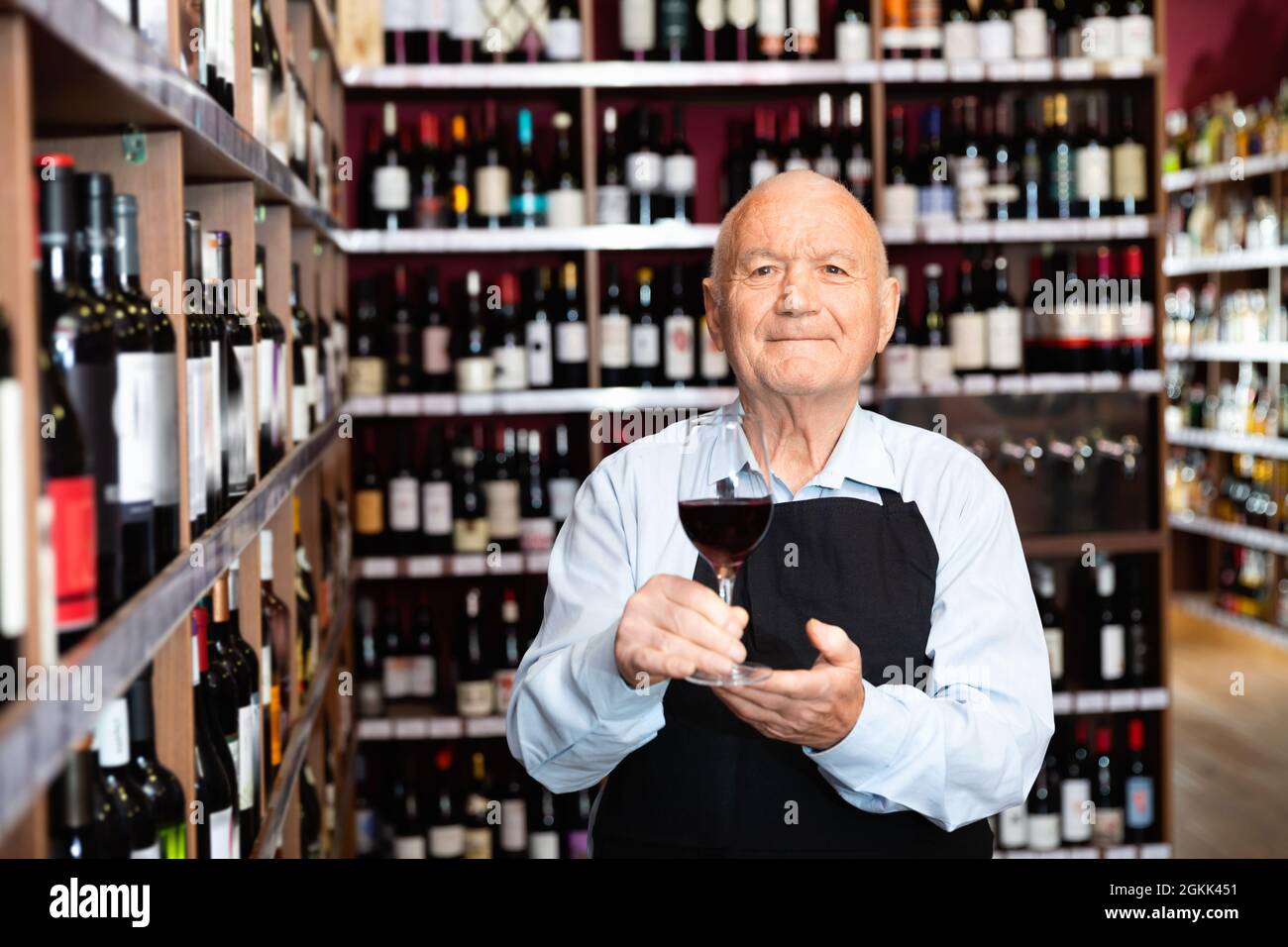Successful elderly male owner of winery inviting to tasting wine of own