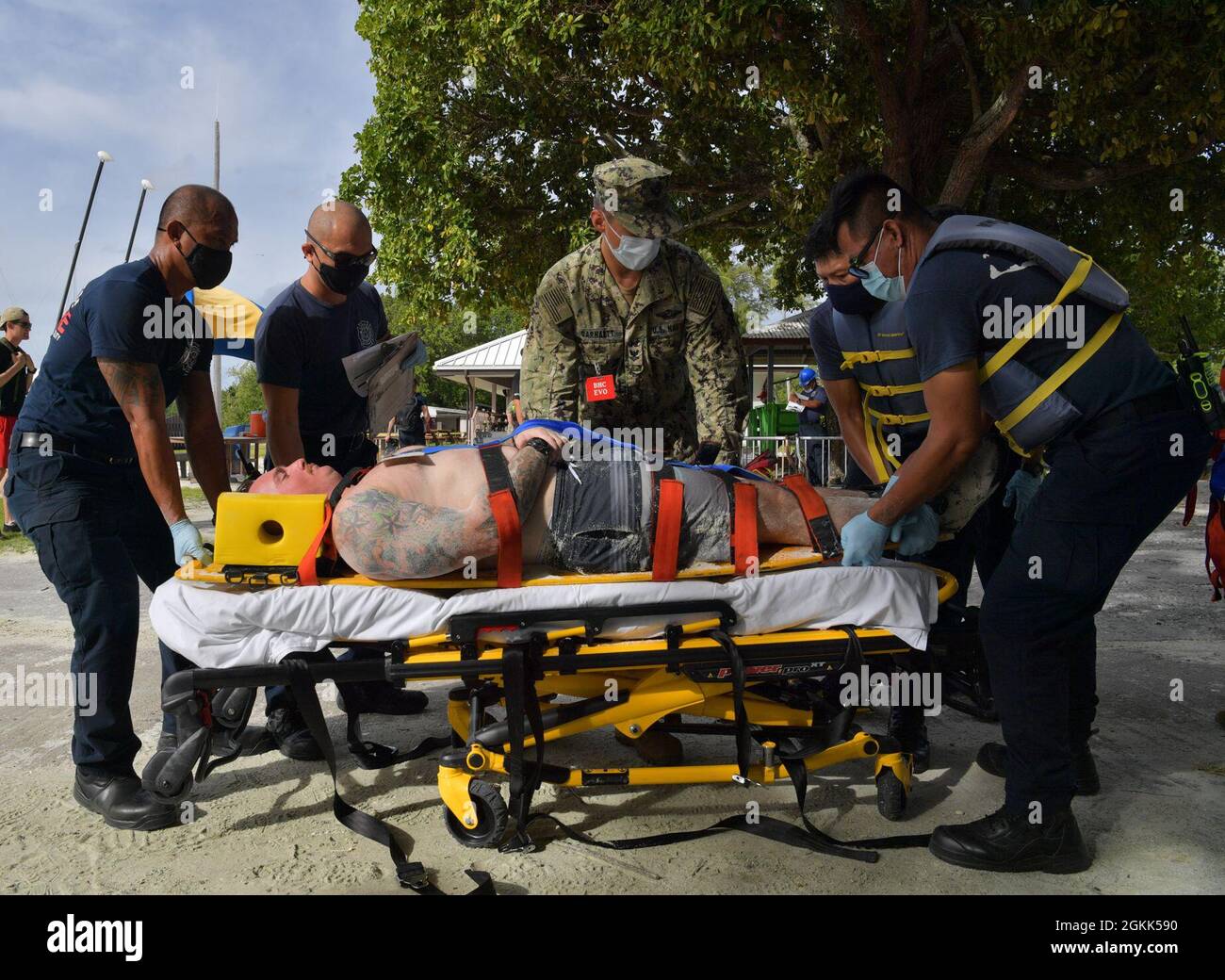 DIEGO GARCIA, British Indian Ocean Territory (May 12, 2021) – U.S. Navy Sailors along with first responders place a wounded shark attack victim on to a gurney during a drill on Diego Garcia, May 12, 2021. U.S. Navy Support Facility Diego Garcia provides logistic, service, recreational and administrative support to U.S. and allied forces forward deployed to the Indian Ocean and Arabian Gulf. Stock Photo