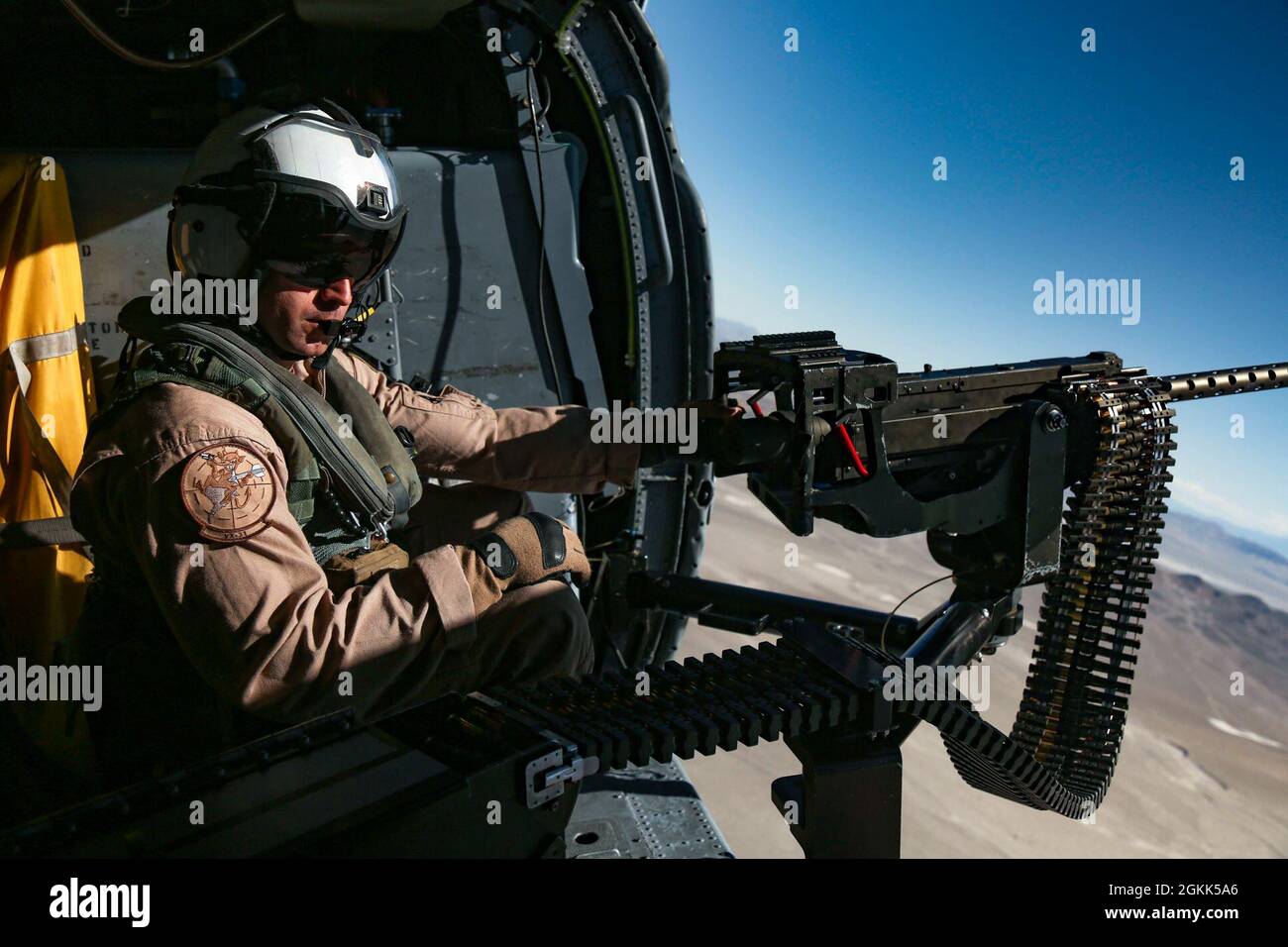210510-N-DN347-1075 FALLON, Nev. (May 11, 2021)  Naval Aircrewman (Helicopter) 1st Class Ian Hamlett, from Santa Cruz, Calif., mans a GAU-21 machine gun in a MH-60S Knighthawk helicopter assigned to the “Chargers” of Helicopter Sea Combat Squadron (HSC) 14, during overland Helicopter Advanced Readiness Program (HARP) training at Naval Air Station, Fallon. HARP is hosted by Helicopter Sea Combat Weapons School Pacific (HSCWSP) and designed to enhance the HSC Community’s realistic war fighting training via joint operations in an austere environment. HSC-14 provides vertical lift search and rescu Stock Photo
