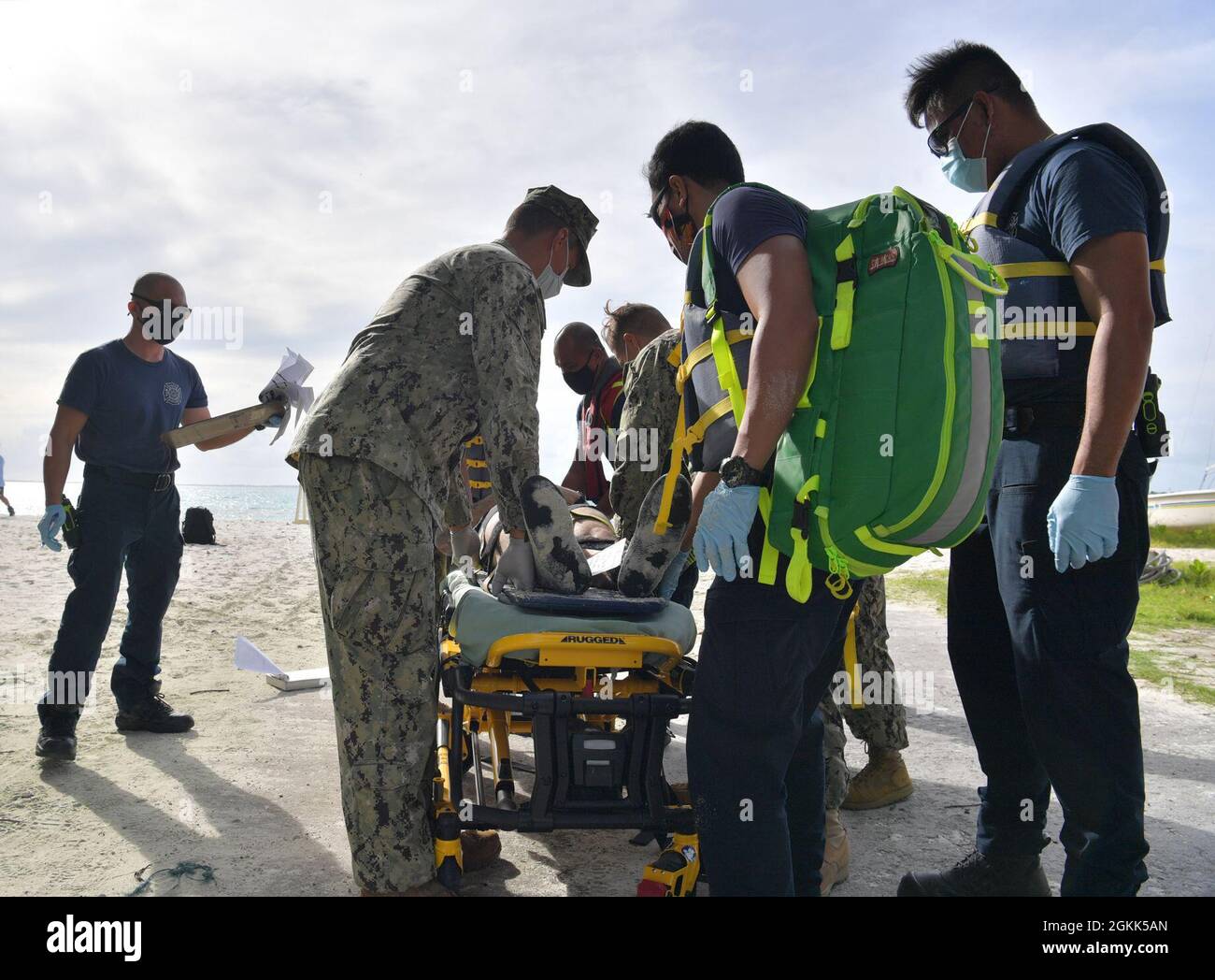 DIEGO GARCIA, British Indian Ocean Territory (May 12, 2021) – U.S. Navy Sailors along with first responders carry a wounded shark attack victim with a stretcher and place them on a gurney during a drill on Diego Garcia, May 12, 2021. U.S. Navy Support Facility Diego Garcia provides logistic, service, recreational and administrative support to U.S. and allied forces forward deployed to the Indian Ocean and Arabian Gulf. Stock Photo