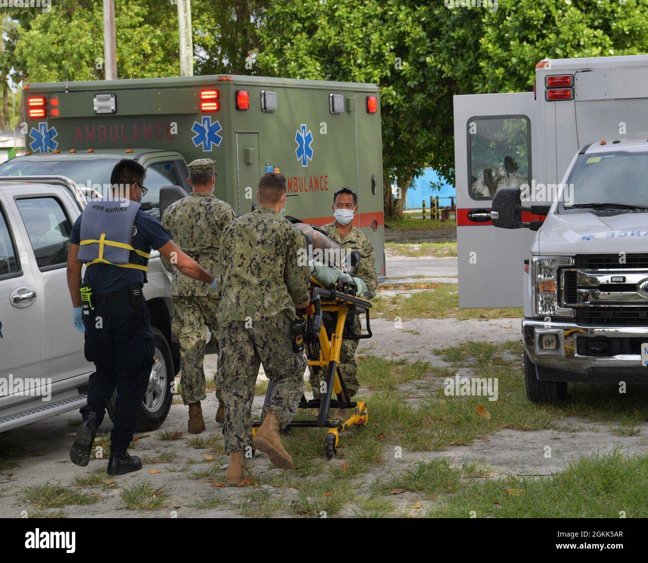 DIEGO GARCIA, British Indian Ocean Territory (May 12, 2021) – U.S. Navy Sailors along with first responders transport a shark attack victim with a gurney to an ambulance during a drill on Diego Garcia, May 12, 2021. U.S. Navy Support Facility Diego Garcia provides logistic, service, recreational and administrative support to U.S. and allied forces forward deployed to the Indian Ocean and Arabian Gulf. Stock Photo