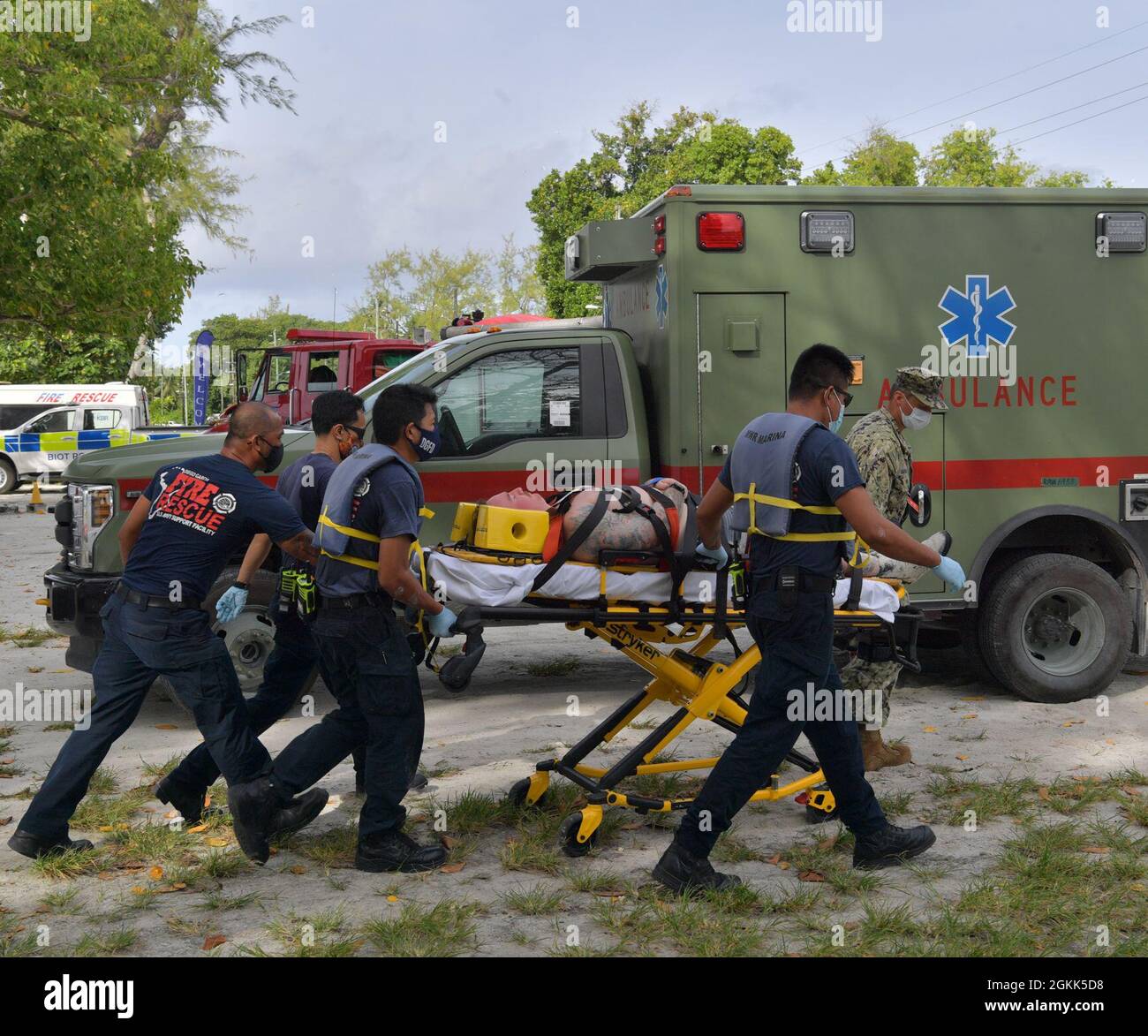 DIEGO GARCIA, British Indian Ocean Territory (May 12, 2021) – U.S. Navy Sailors along with first responders transport a shark attack victim with a gurney to an ambulance during a drill on Diego Garcia, May 12, 2021. U.S. Navy Support Facility Diego Garcia provides logistic, service, recreational and administrative support to U.S. and allied forces forward deployed to the Indian Ocean and Arabian Gulf. Stock Photo