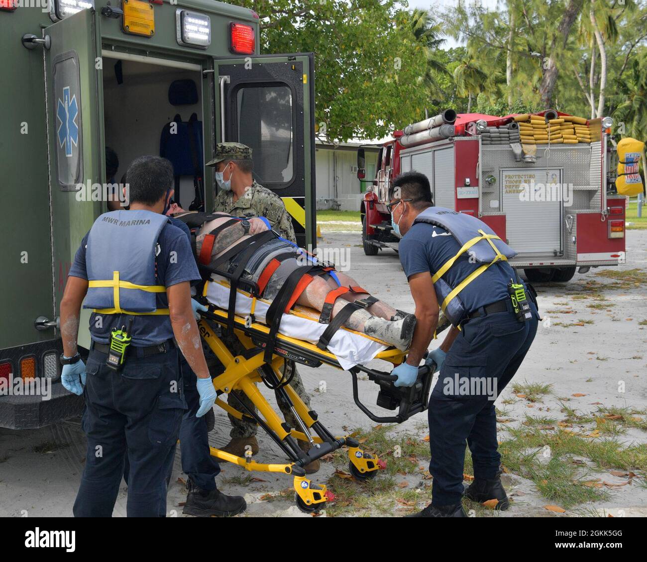 DIEGO GARCIA, British Indian Ocean Territory (May 12, 2021) – U.S. Navy Sailors along with first responders transport a shark attack victim into an ambulance during a drill on Diego Garcia, May 12, 2021. U.S. Navy Support Facility Diego Garcia provides logistic, service, recreational and administrative support to U.S. and allied forces forward deployed to the Indian Ocean and Arabian Gulf. Stock Photo