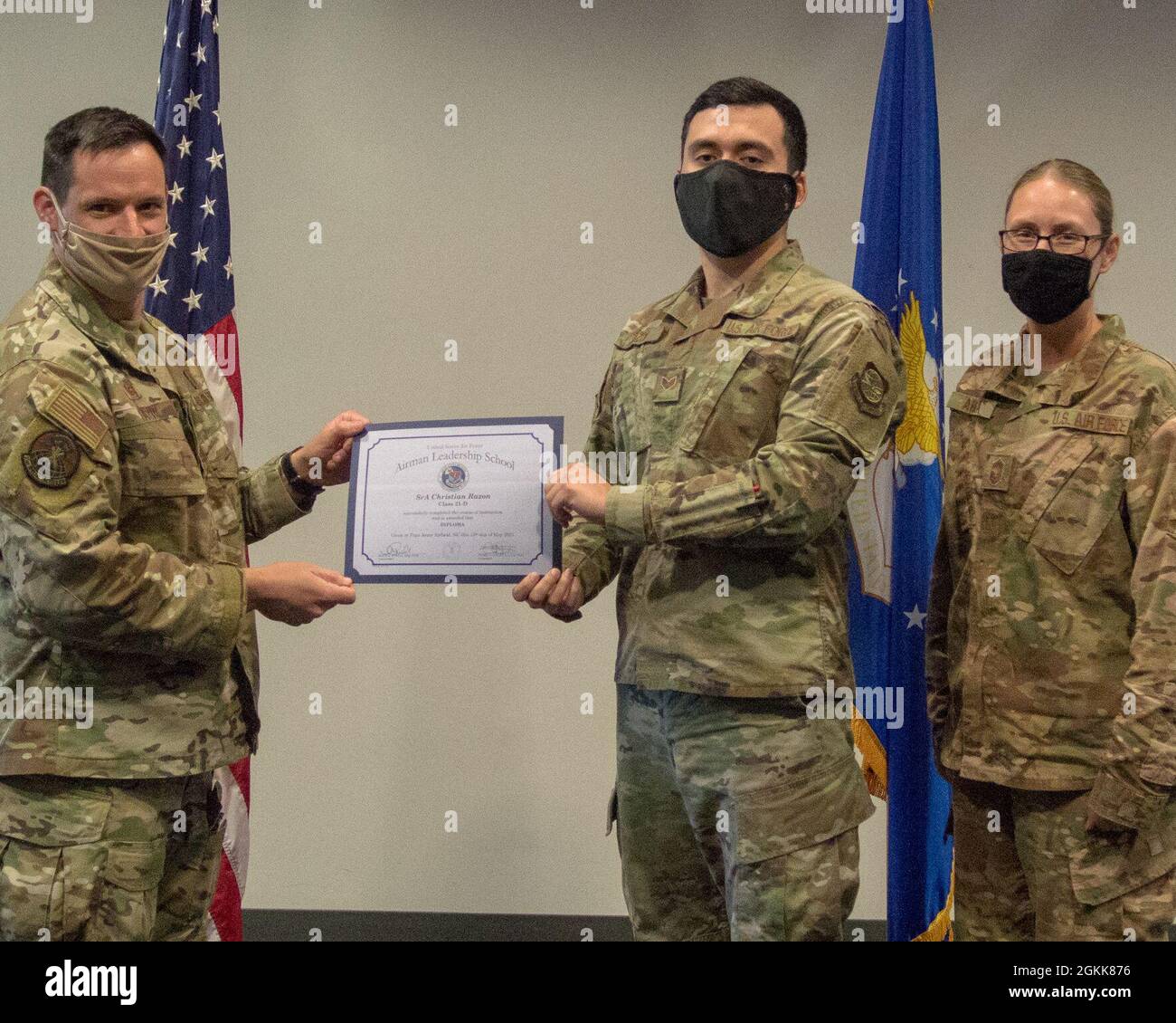 U.S. Air Force Senior Airman Christian Razon, 43rd Air Mobiliity Squadron, receives a graduation certificate from Lt Col. Michael Fazio, 21st Special Tactics Squadron commander, and Chief Master Sgt. Mariah Armga, 43 AMOG superintedent. The presentation was part of the graduation ceremony for Class 21-D of the Chief Master Sgt. Louis Williams Airman Leadership School at Pope Army Airfield, North Carolina, May 13, 2021. Stock Photo