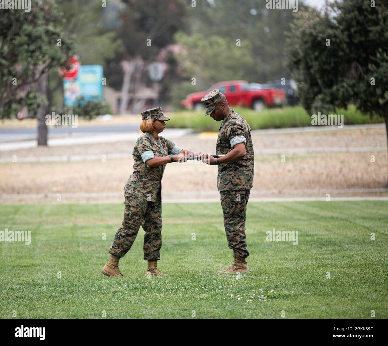 Sgt. Maj. Ronda R. Kirkby, outgoing sergeant major, Combat Logistics Regiment 17, passes the noncommissioned officer sword to Col. Nick I. Brown, commanding officer, CLR-17, signifying the official transfer of her duties as the command’s senior enlisted advisor during a combined relief and appointment and change of command ceremony at Marine Corps Base Camp Pendleton, May 13, 2021. Stock Photo