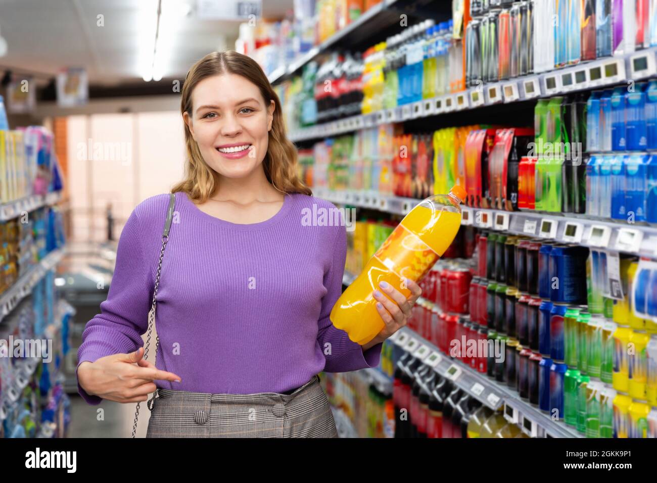 Portrait of young happy woman satisfied with choosed carbonated soft drinks in food store Stock Photo